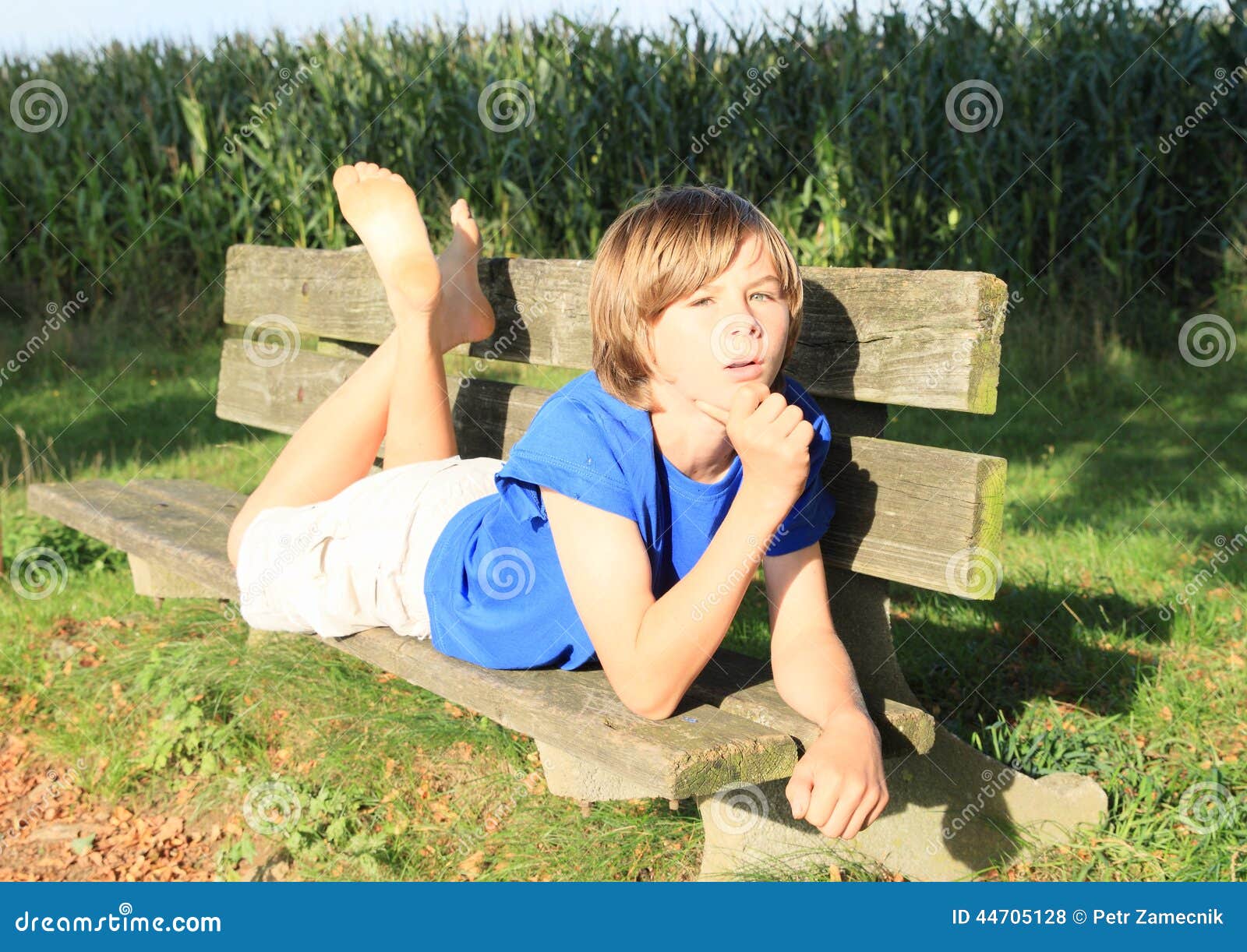 little kid boy bench cute barefoot lying wooden corn field behind 44705128