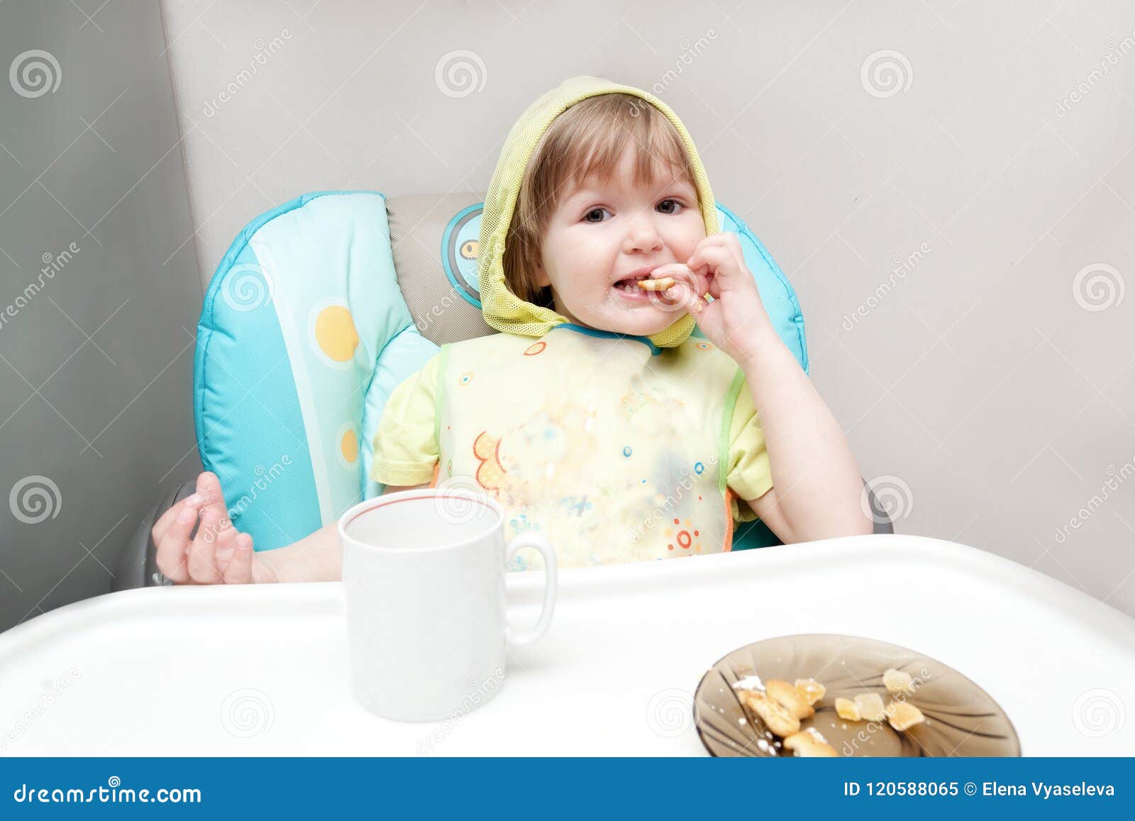Little One Year Old Baby Girl Is Eating At The Highchair Stock