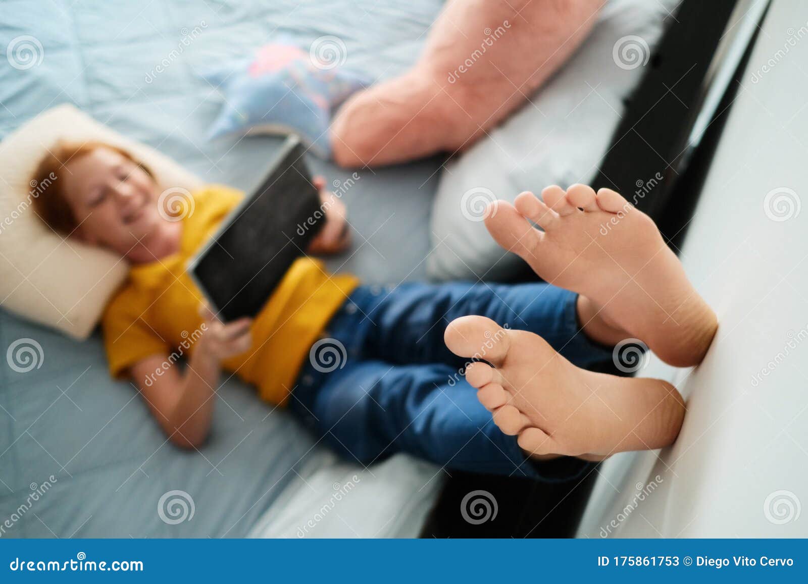 little redhead girl watching cartoons at home with tablet