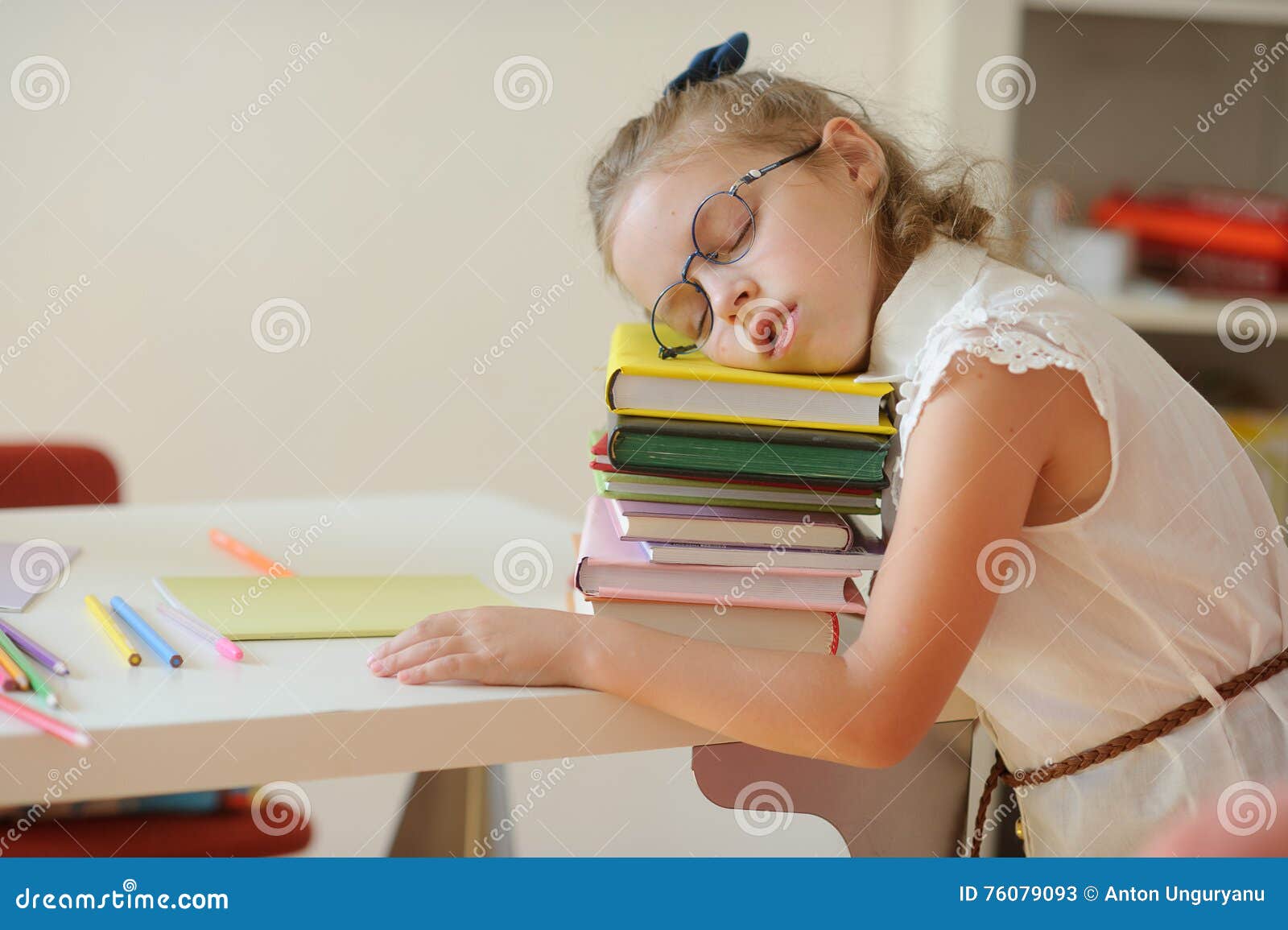 little schoolgirl fall asleep on a pile of books.