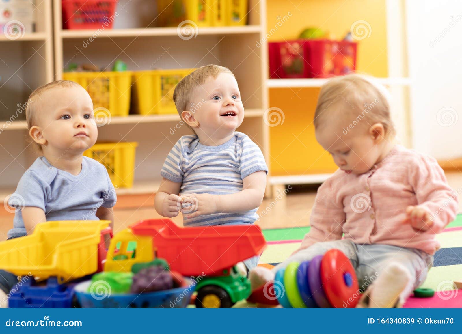 little toddlers boys and a girl playing together in kindergarten room. preschool children in day care centre