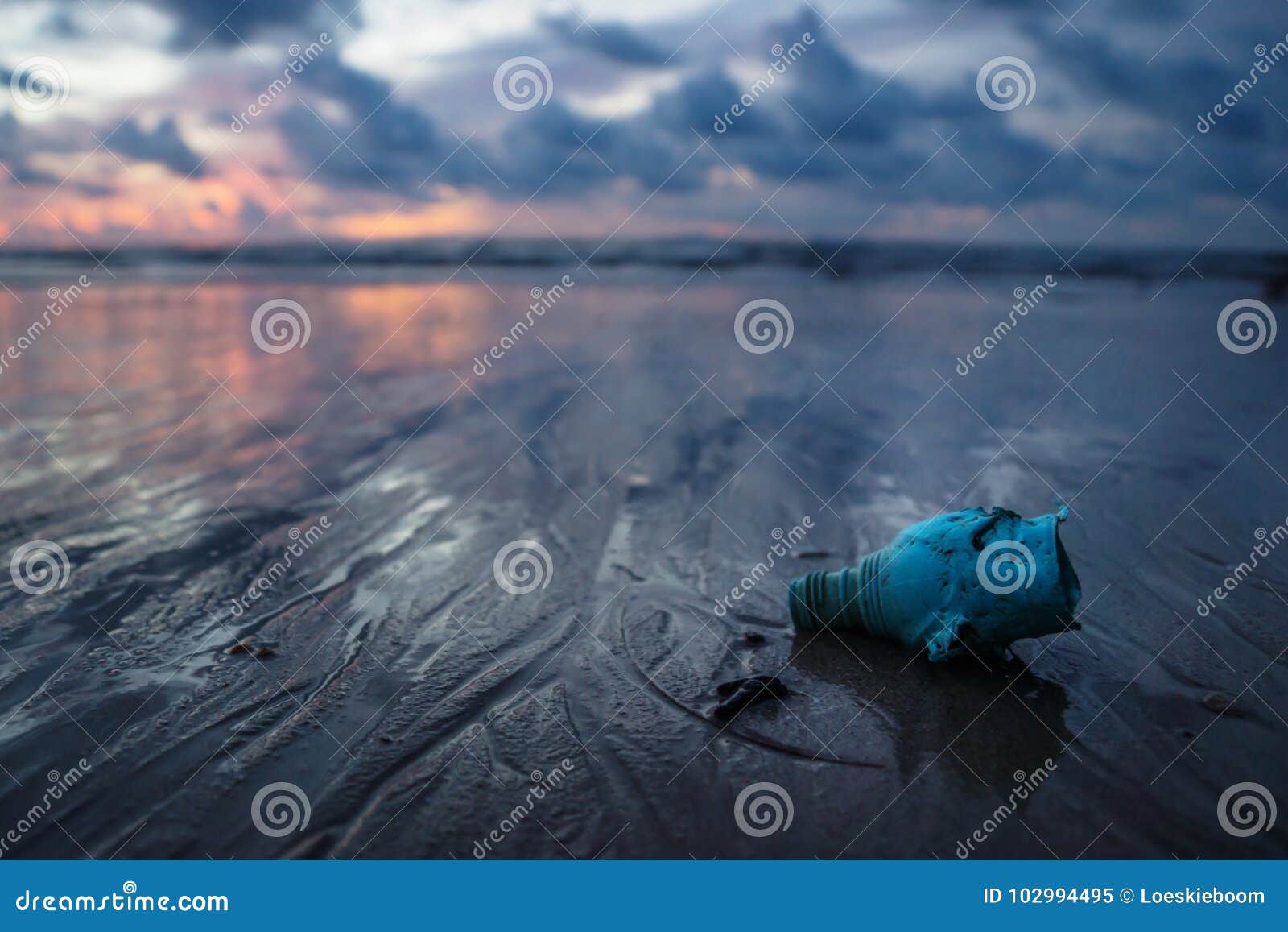 Lixo plástico que desarruma o oceano na praia durante o por do sol, Koh Lanta, Tailândia. A garrafa, garbish plásticos e trash a desordem do oceano na praia durante o por do sol, Koh Lanta, Tailândia