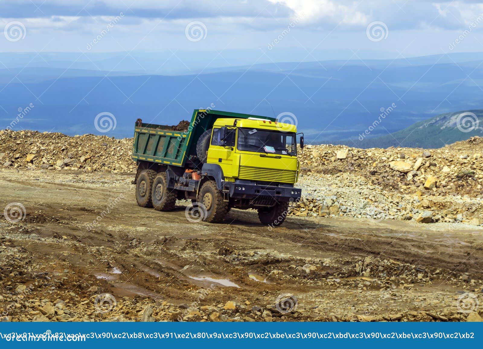 Dump truck is driving on a mountain road. Loaded dump truck rides on the mountain road under construction