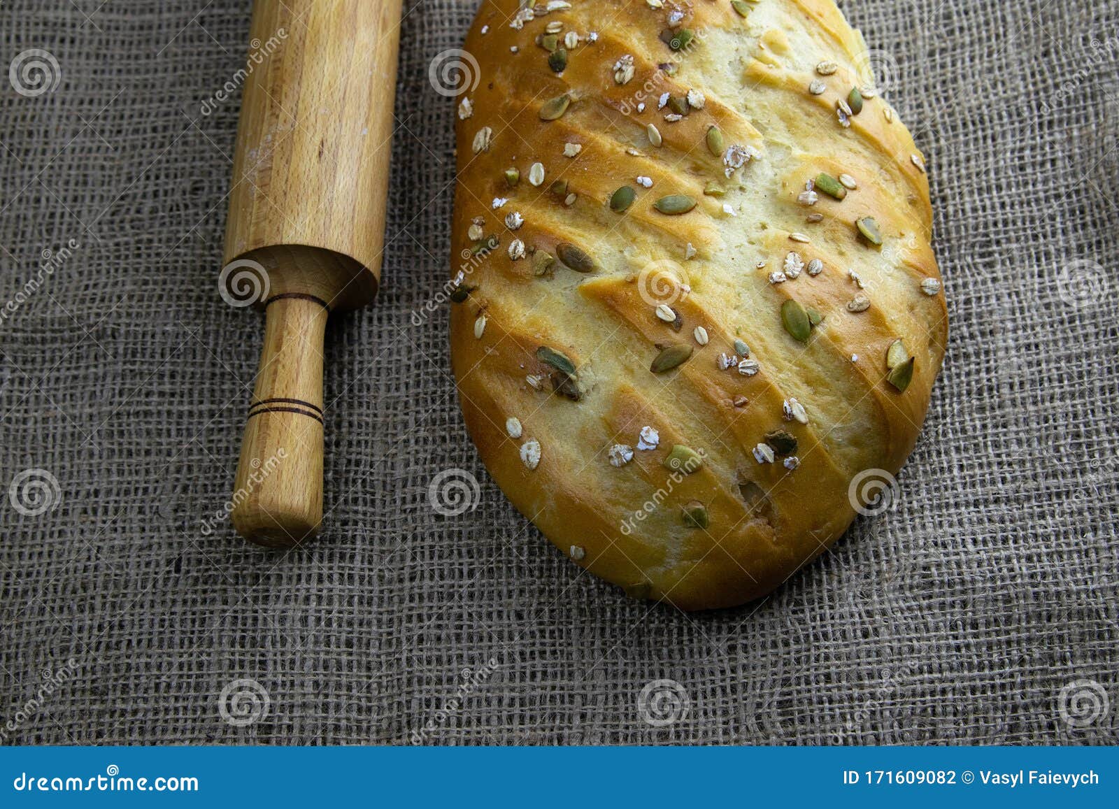 A Loaf of Bread with a Rolling Pin for Dough Stand on a Craft Linen Bag