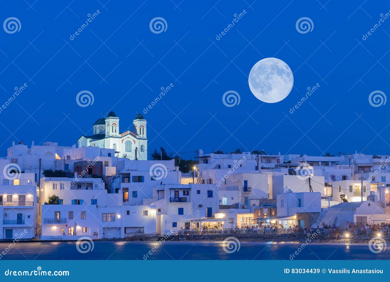local church of naoussa village at paros island in greece against the full moon.