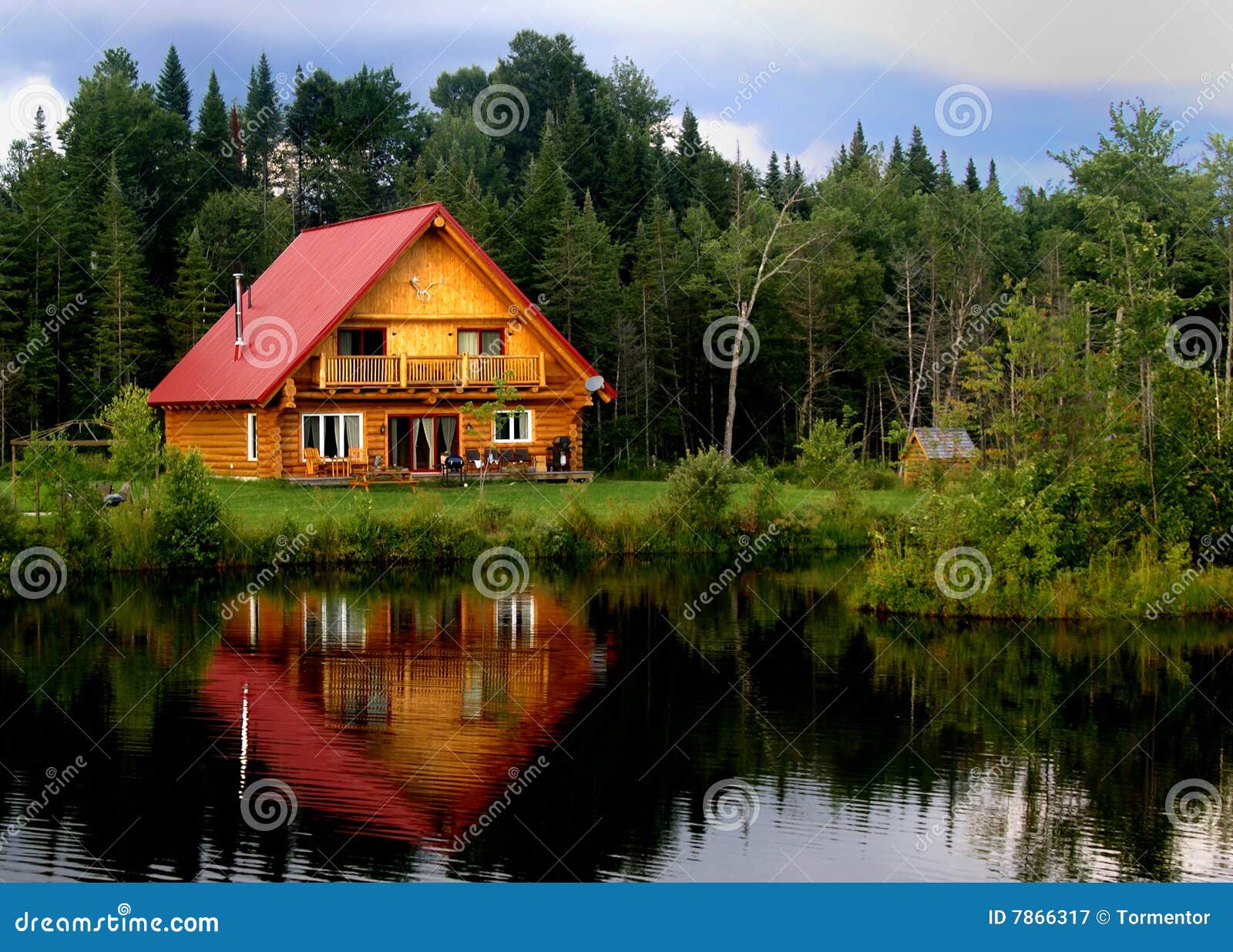 A beautiful log cabin on a lake, with reflections in the water.