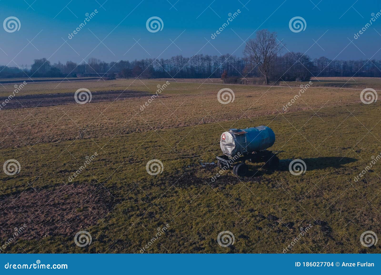 a lonely manure tank or cistern standing in the middle of the field. some fertilizer was spilled around the tank