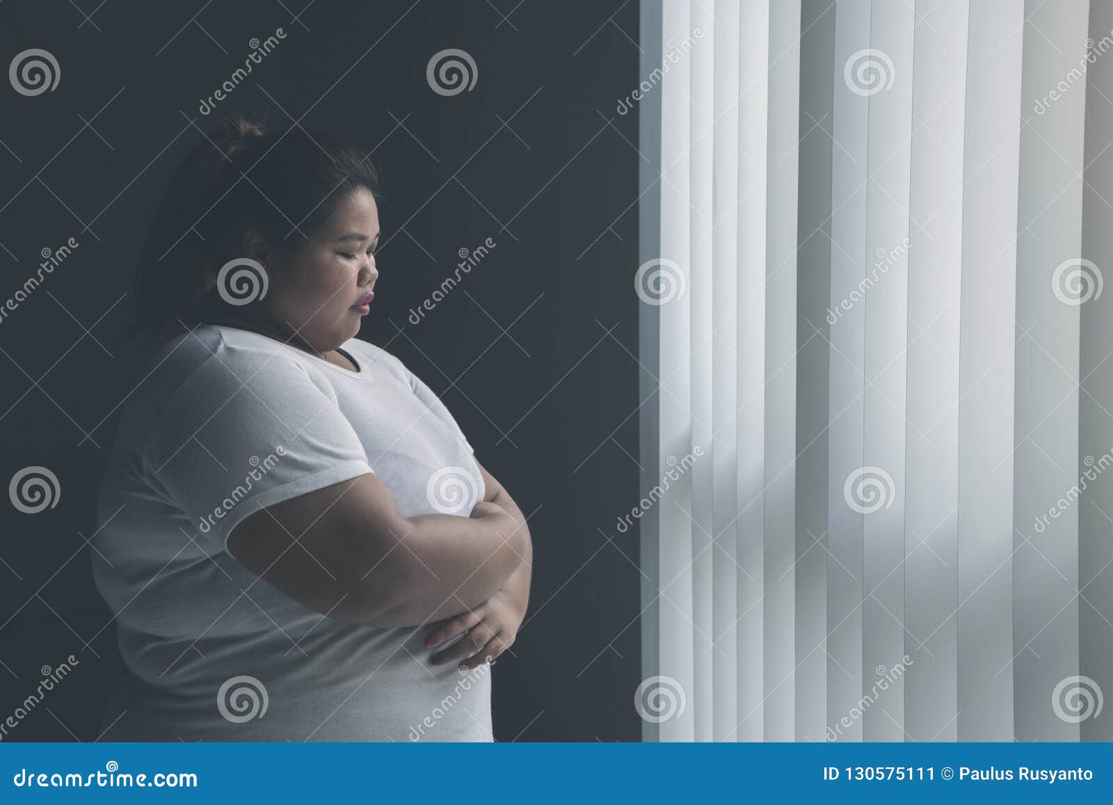 lonely obese woman standing near the window