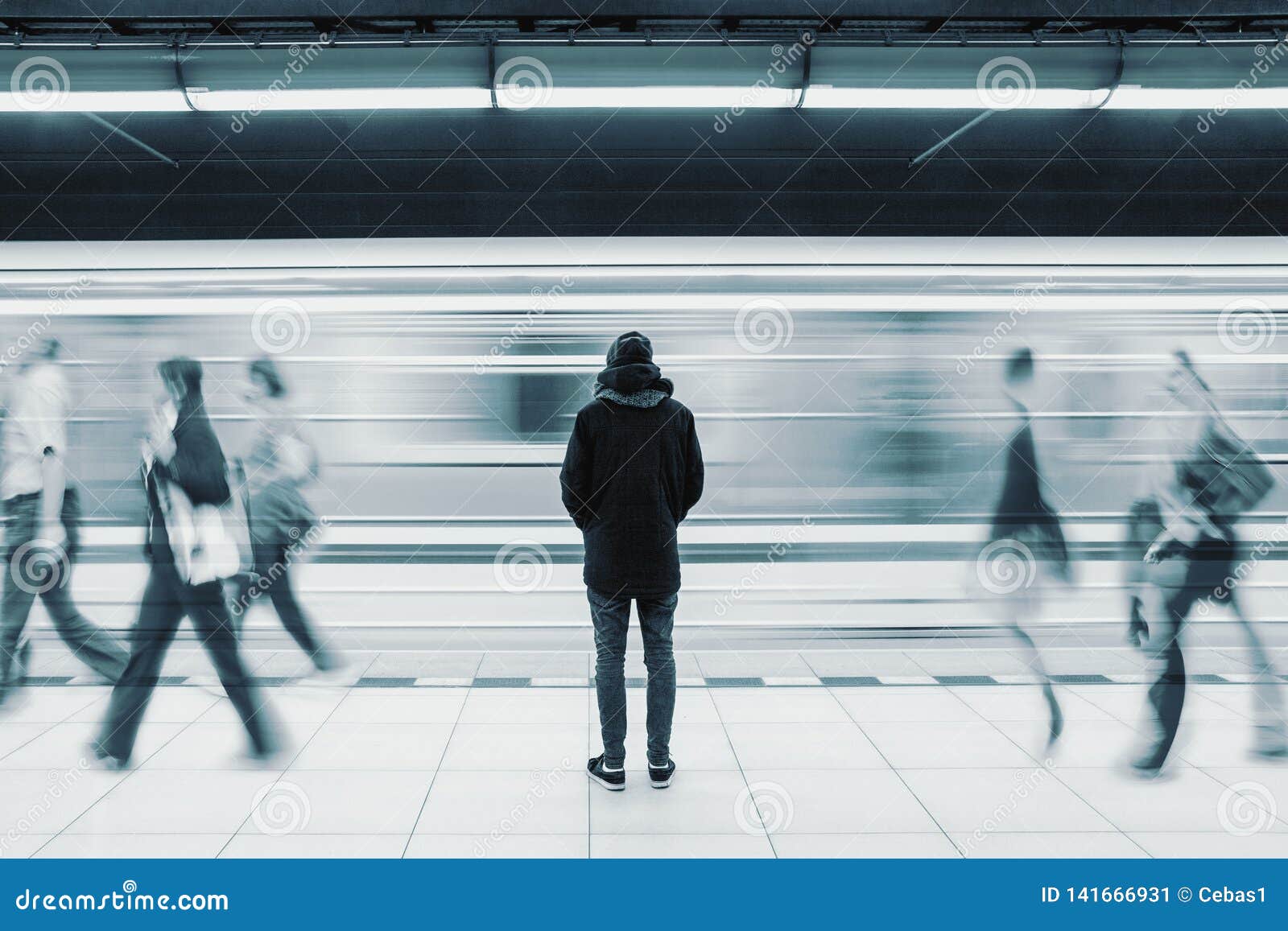 long exposure picture with lonely man at subway station with blurry moving train and walking people