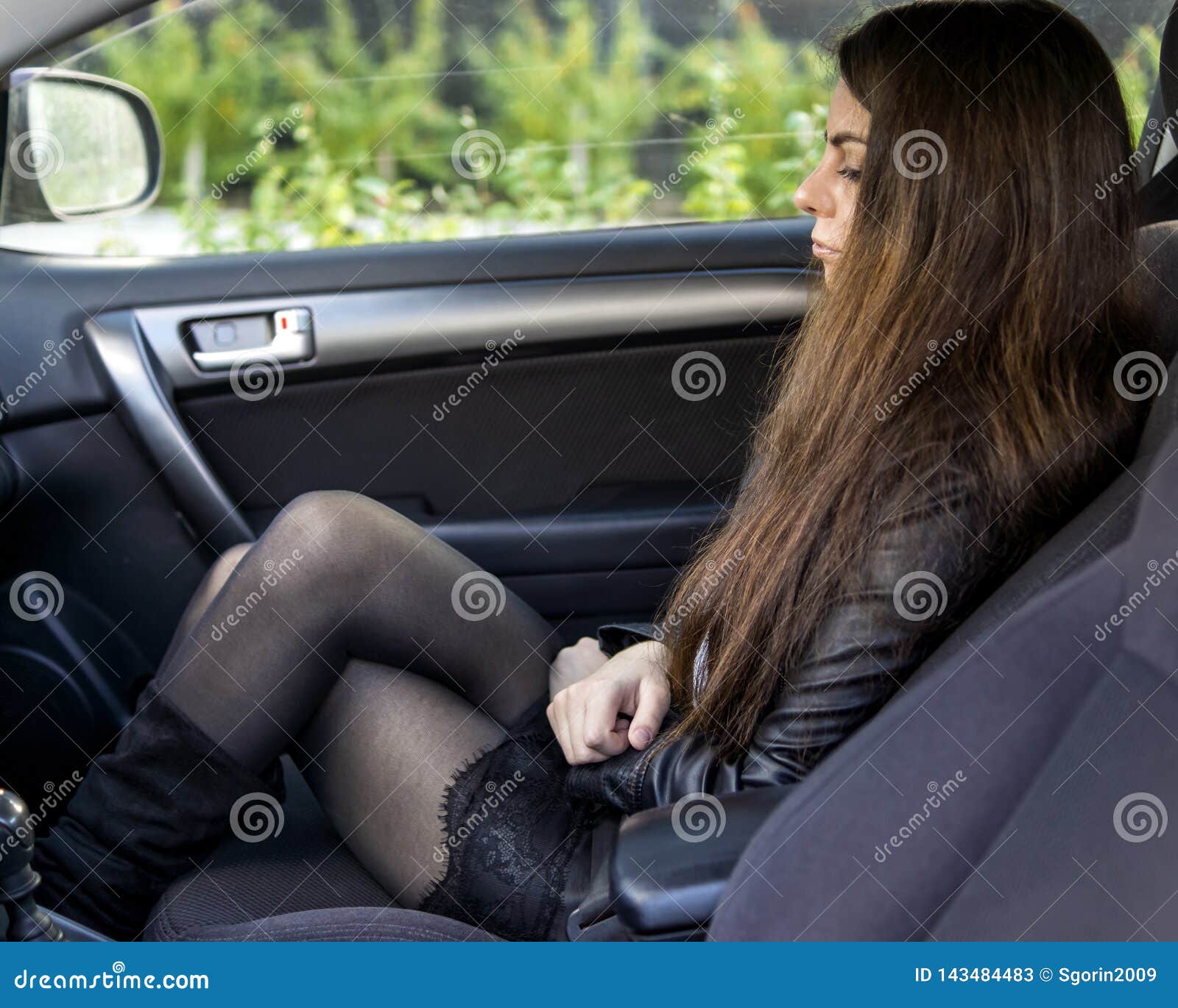 young girl with seductive legs in black pantyhose and short skirt in car