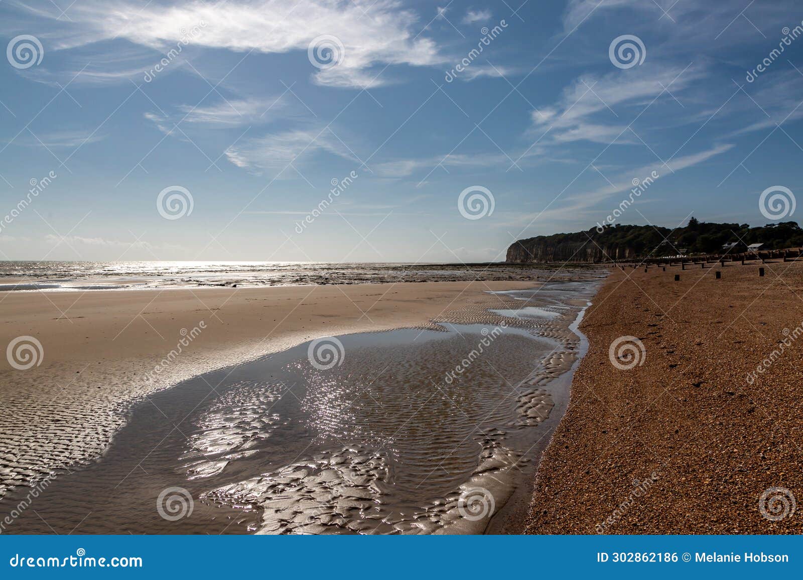 looking along the beach at pett level on the sussex coast, with the sun shimmering on the water