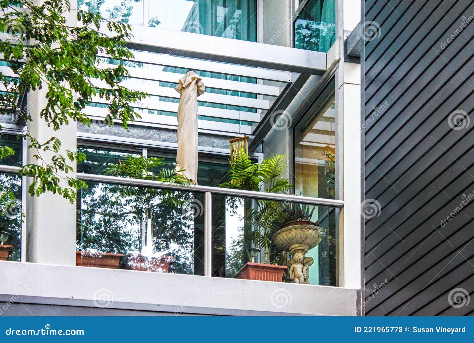 looking up al elegant modern balcony with interesting archetecture and potted plants and an umbrella
