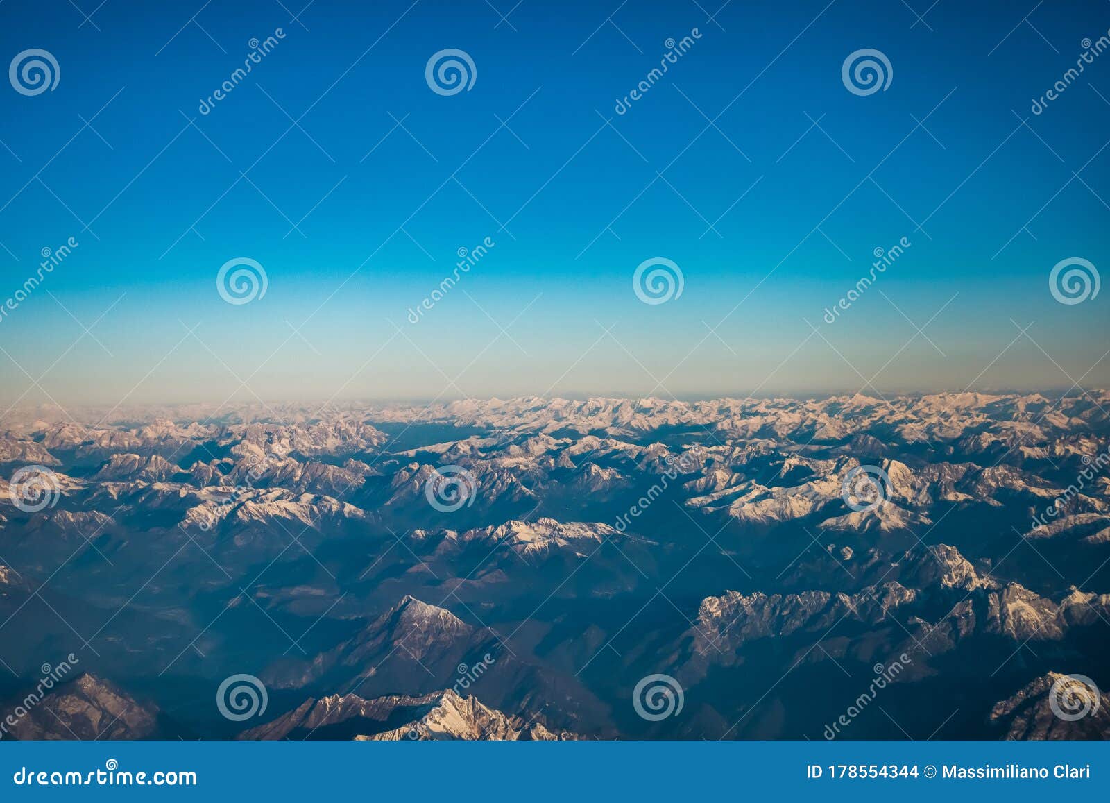 looking through the window aircraft during flight a snow covered italian and osterreich alps with blue sky without clouds