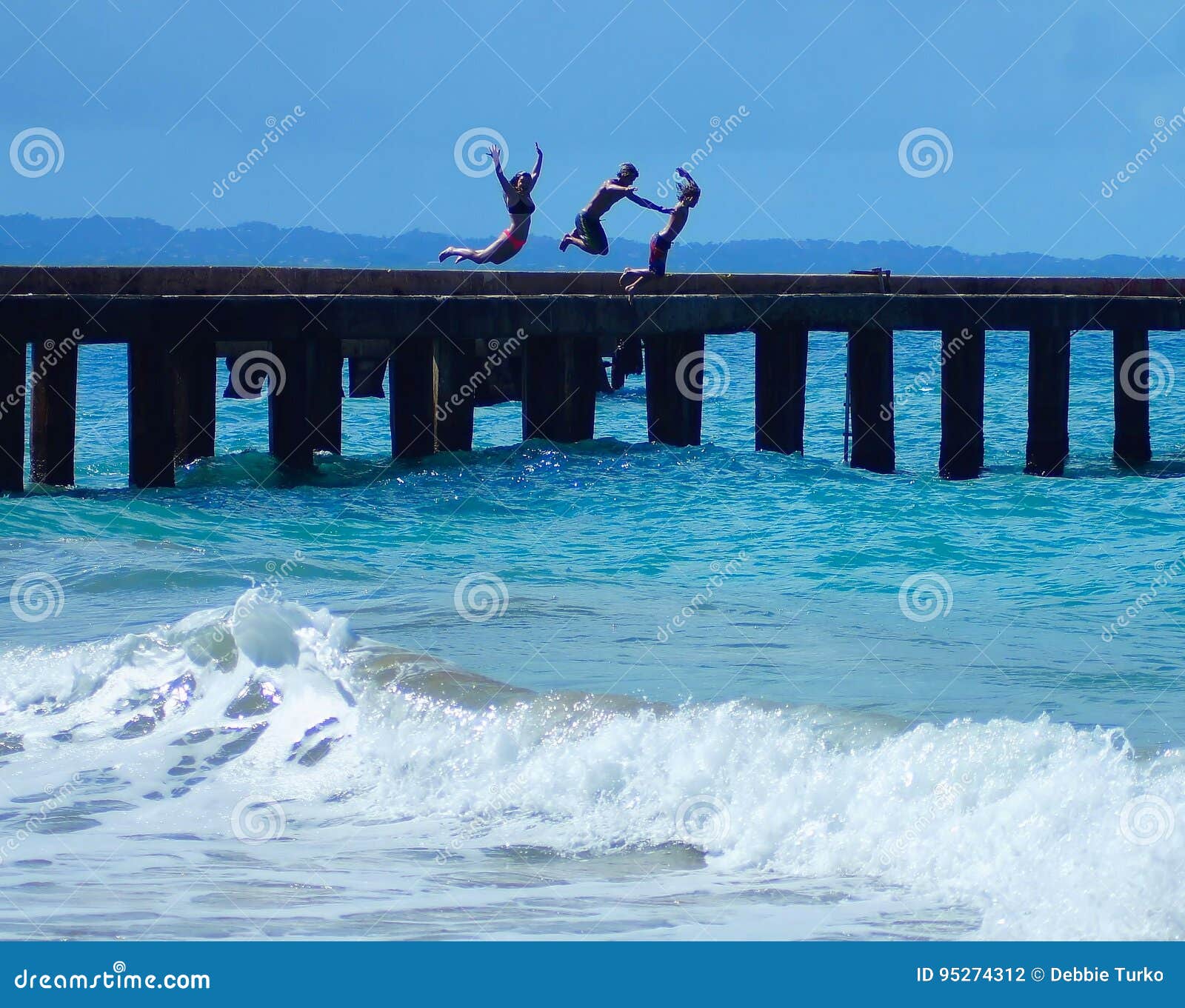 Los niños que saltan de Pier Into Ocean en Puerto Rico. ¡Niños que disfrutan de la emoción de la aventura saltando de este embarcadero viejo en el océano del Caribe hermoso en los barcos de desplome, Aguadilla Puerto Rico!