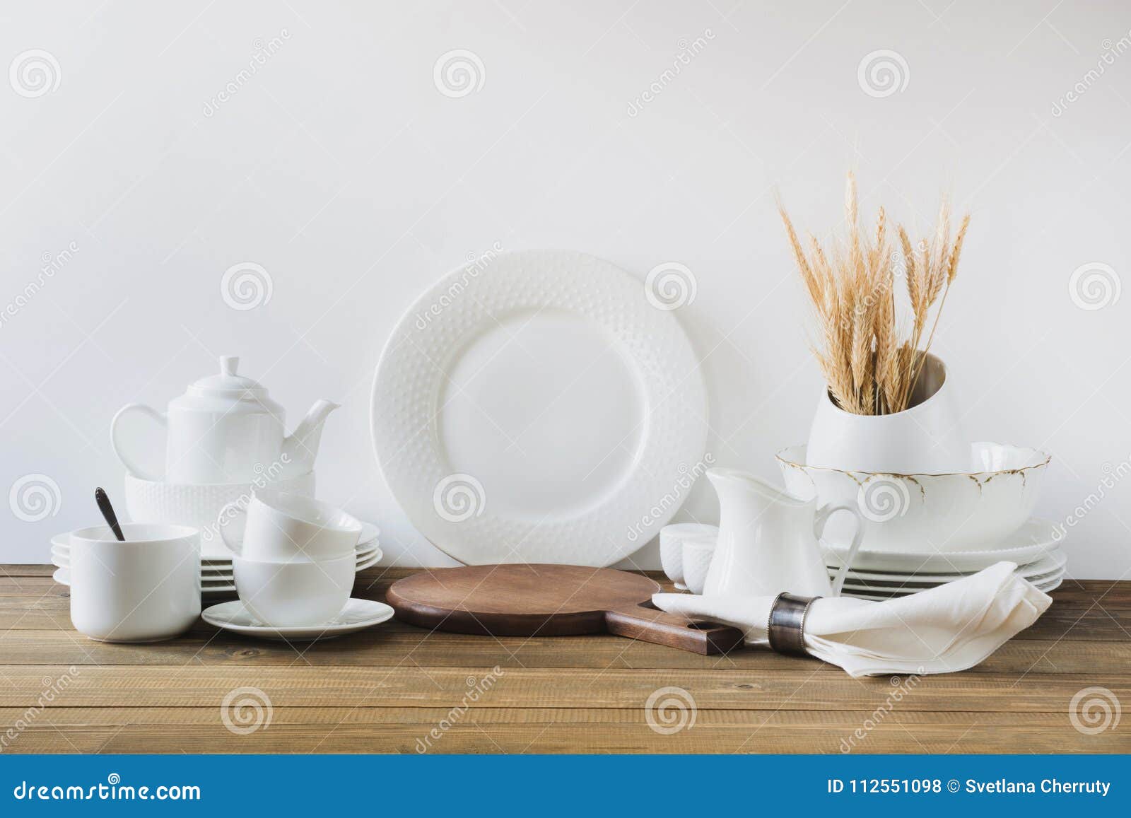 Los utensilios blancos de la cocina, el dishware y otra diversa materia blanca para servir en el tablero de madera blanco Copie el espacio