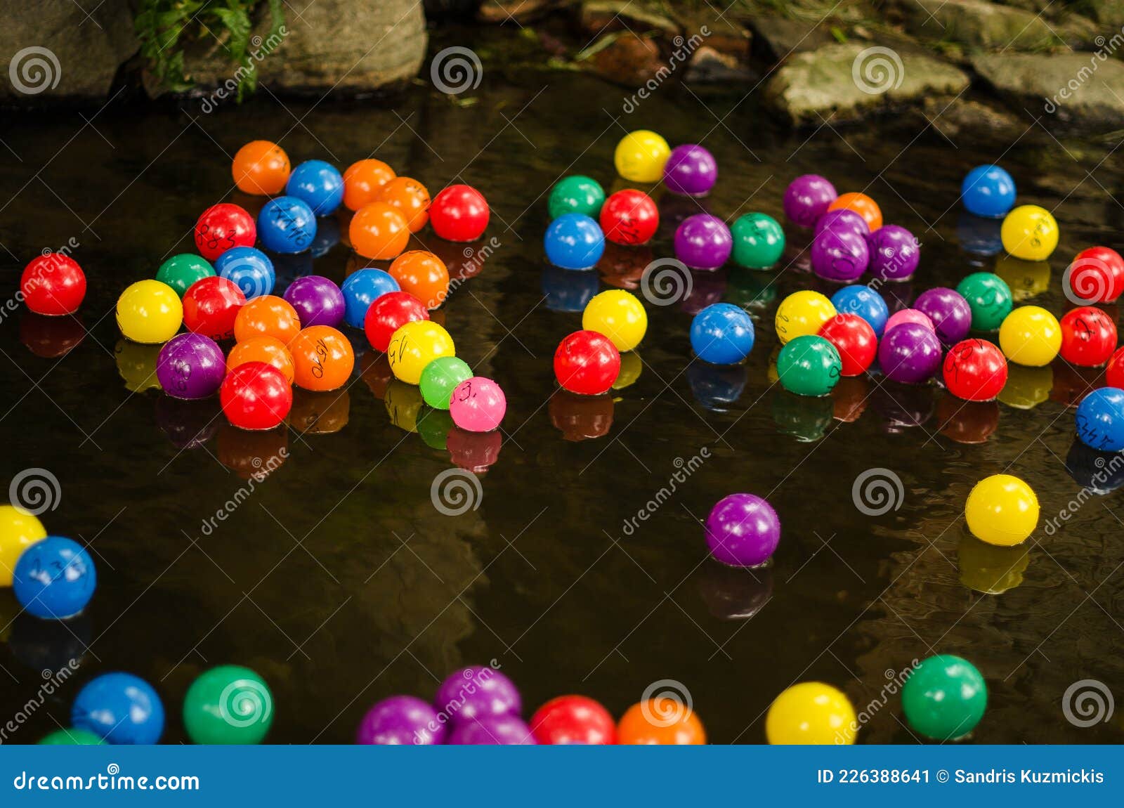 Lots of Colorful Plastic Balls with Numbers in the River Stock Image
