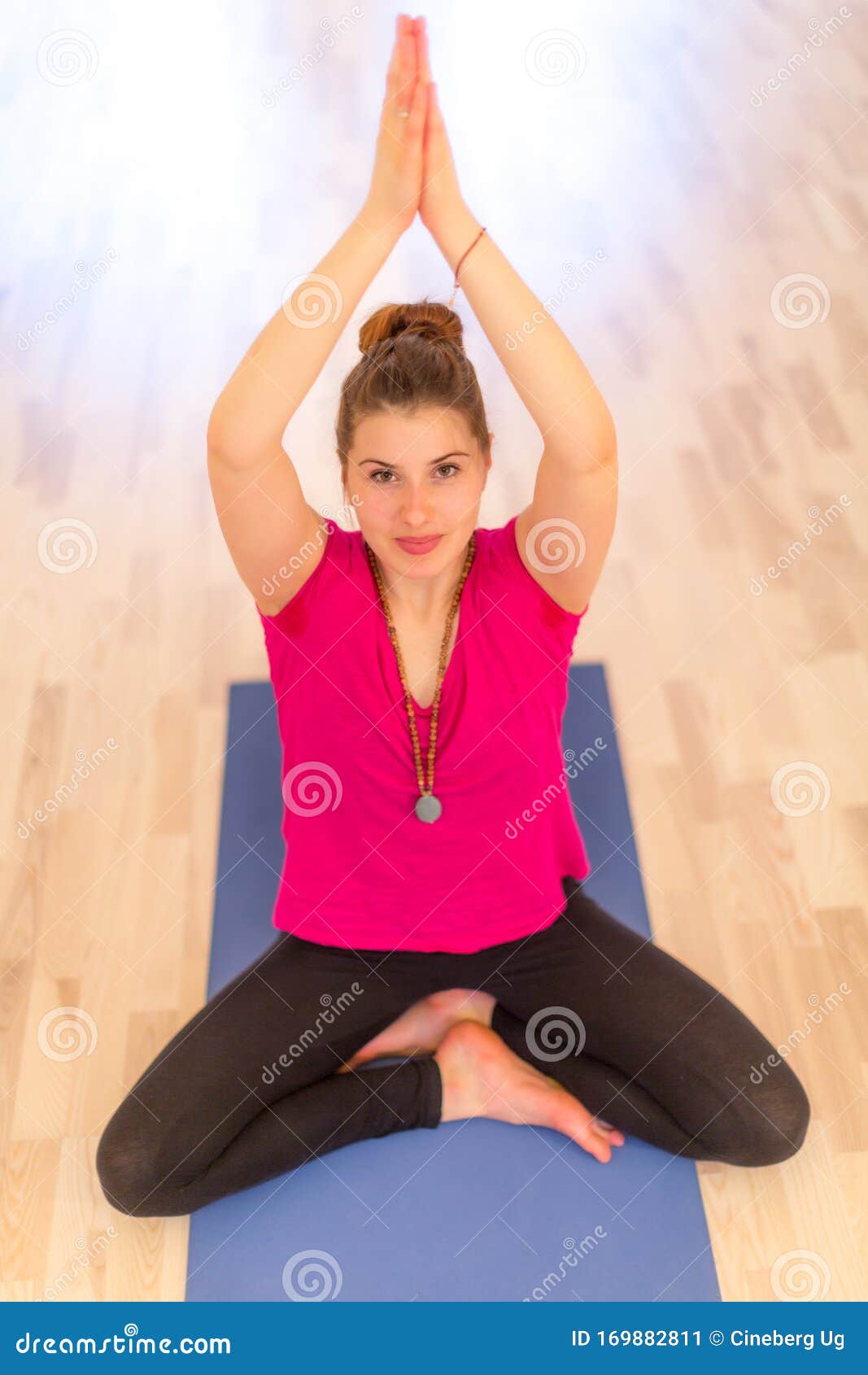 Cropped view of woman sitting cross legged, hands together meditating -  Stock Photo - Dissolve