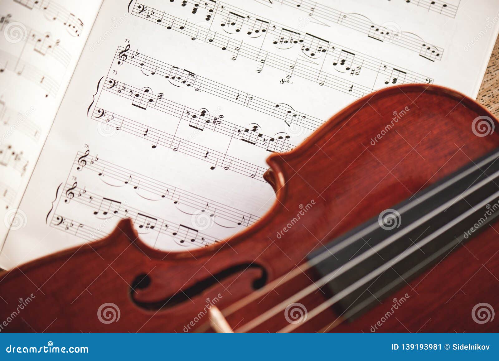 in love with classic music. close up view of brown violin lying on music score sheet. violin lessons