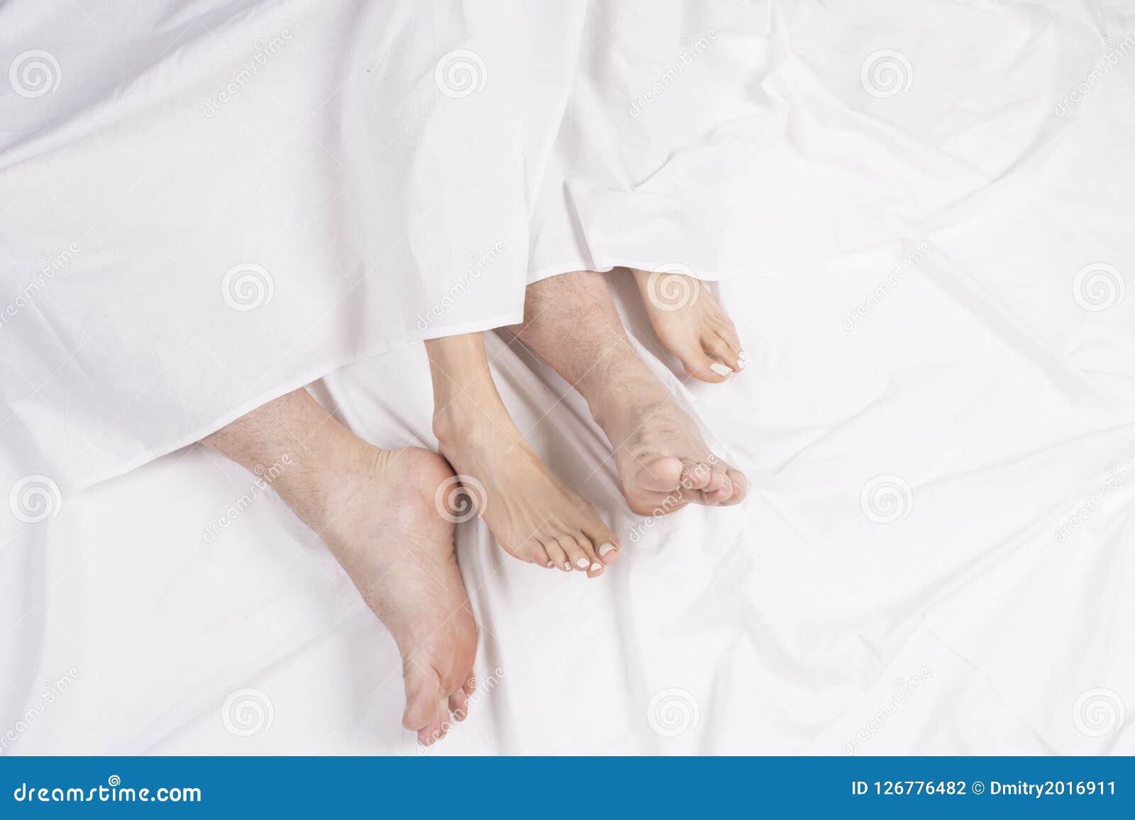 Love Lying in Bed, Embracing on White Sheets, Close Up Legs. Stock