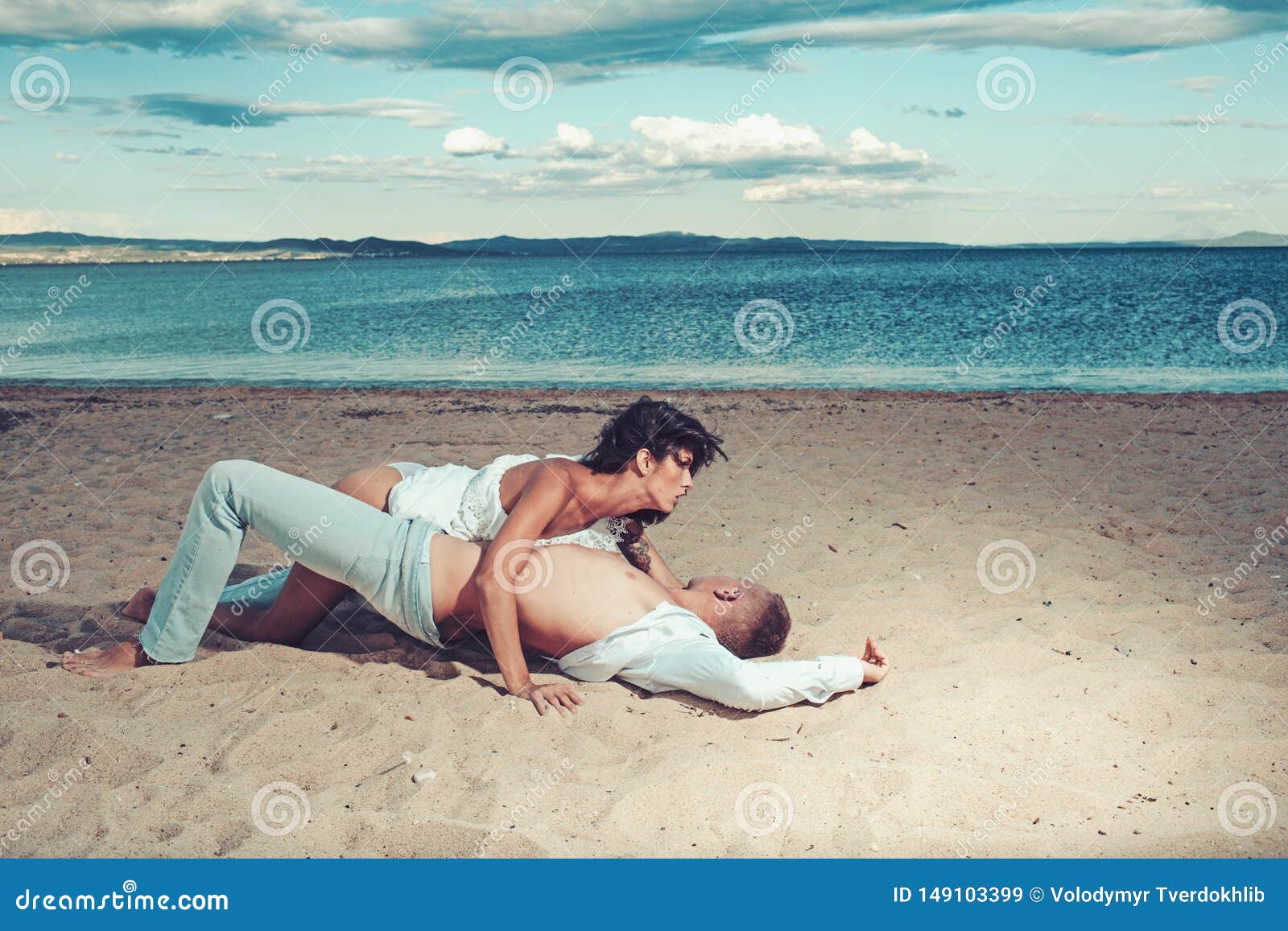 Cheerful couple having some good time naked on the beach