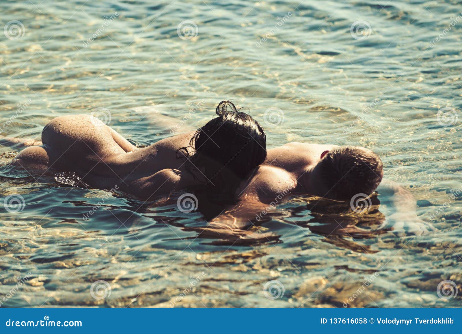 Two alluring women are relaxing on the nudist beach