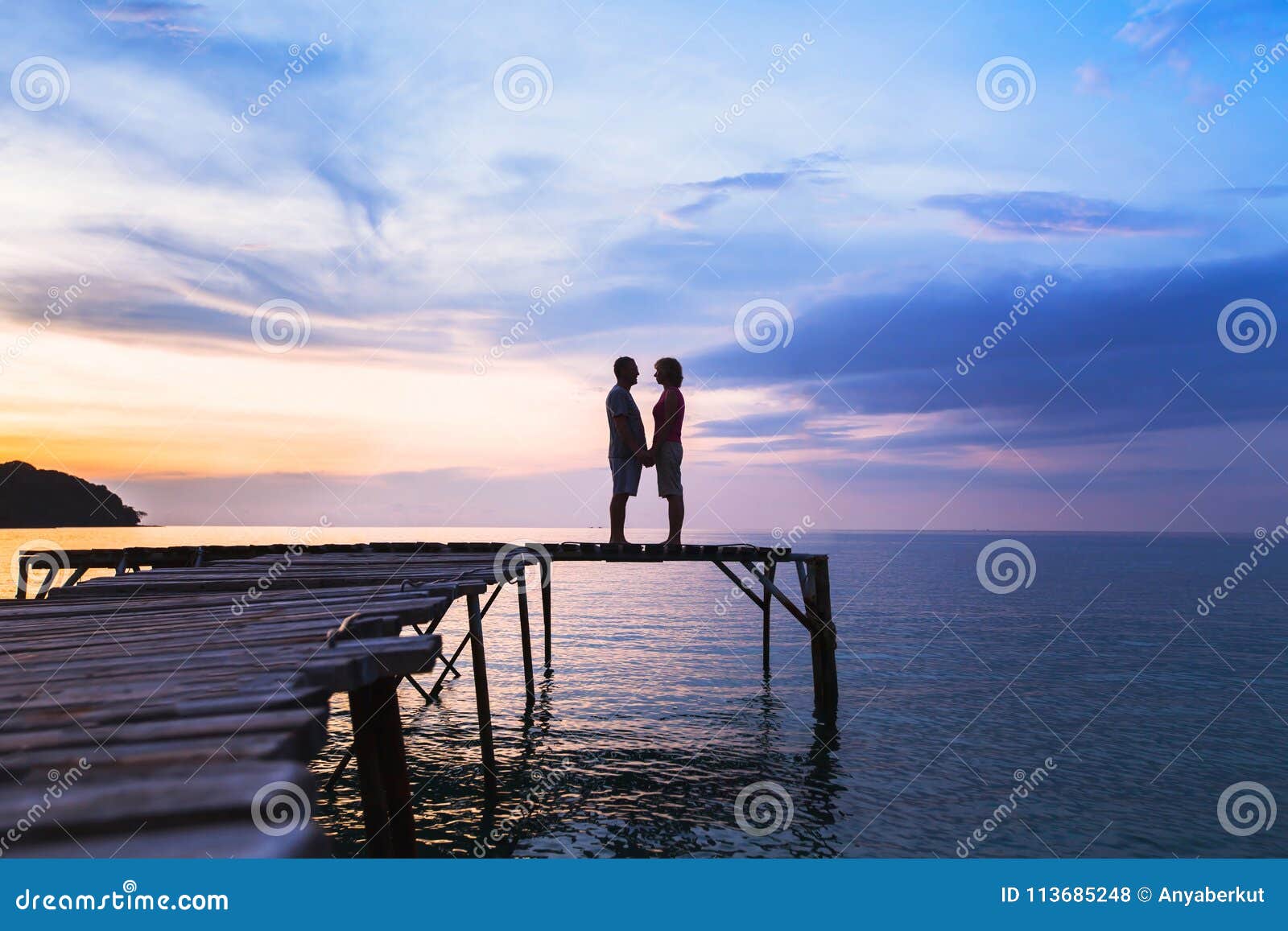 love, silhouette of affectionate couple on the pier at sunset beach