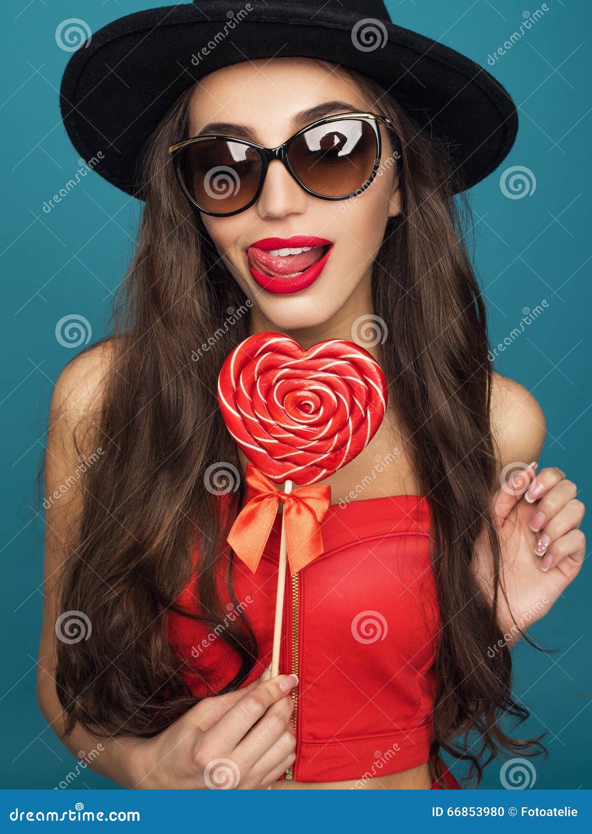 Love and valentines day, woman with sly smile holding heart. Portrait of Beautiful woman in hat with bright makeup and red heart in hand.