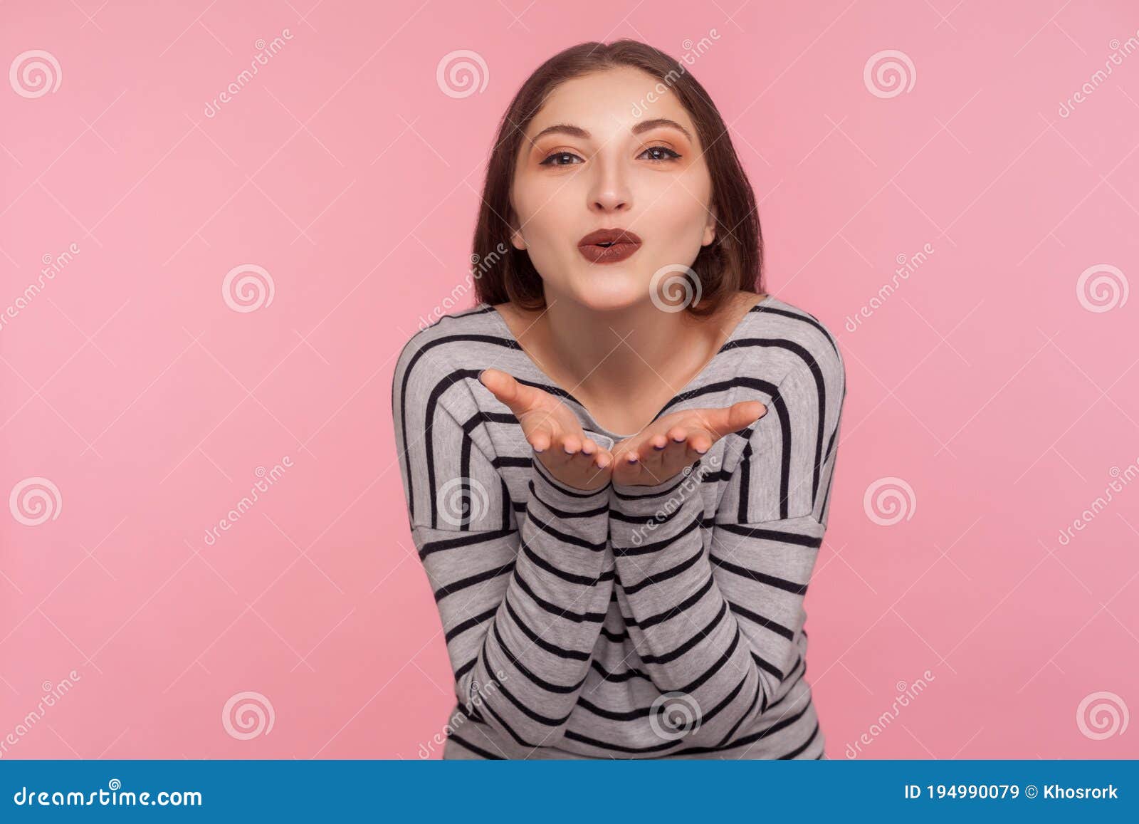 love you! portrait of sensual attractive woman in striped sweatshirt sending air kiss over palms, expressing fondness