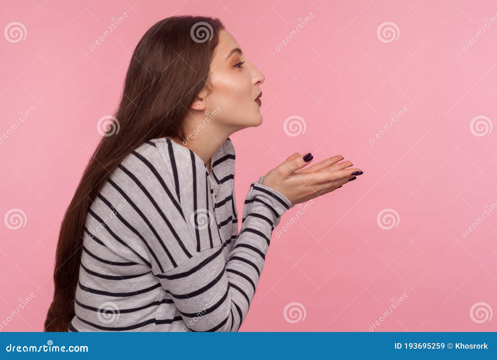 love you! side view of sensual attractive woman in striped sweatshirt sending air kiss over palms, expressing fondness