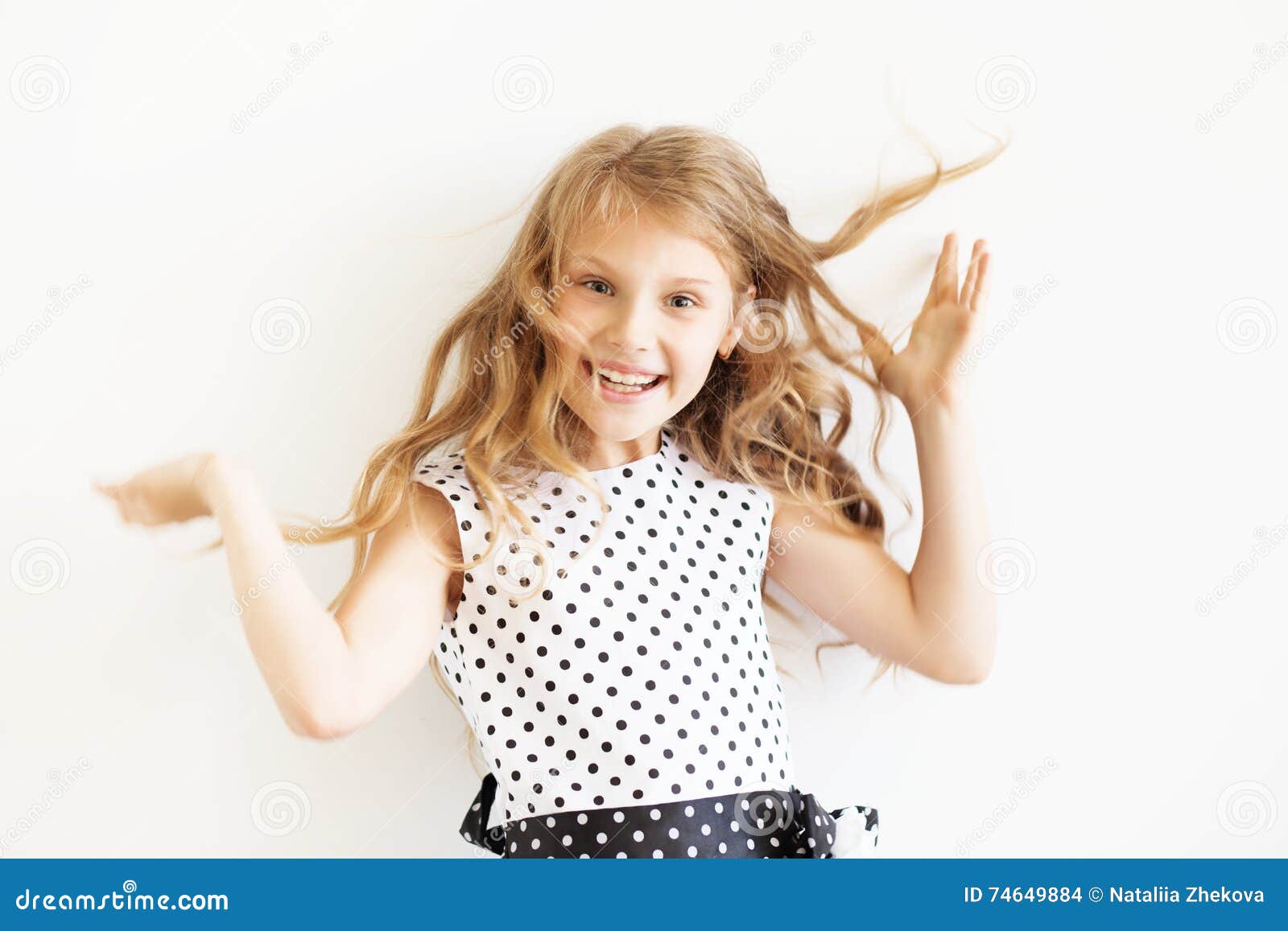 lovely frisky little girl in a polka-dot dress against a white b