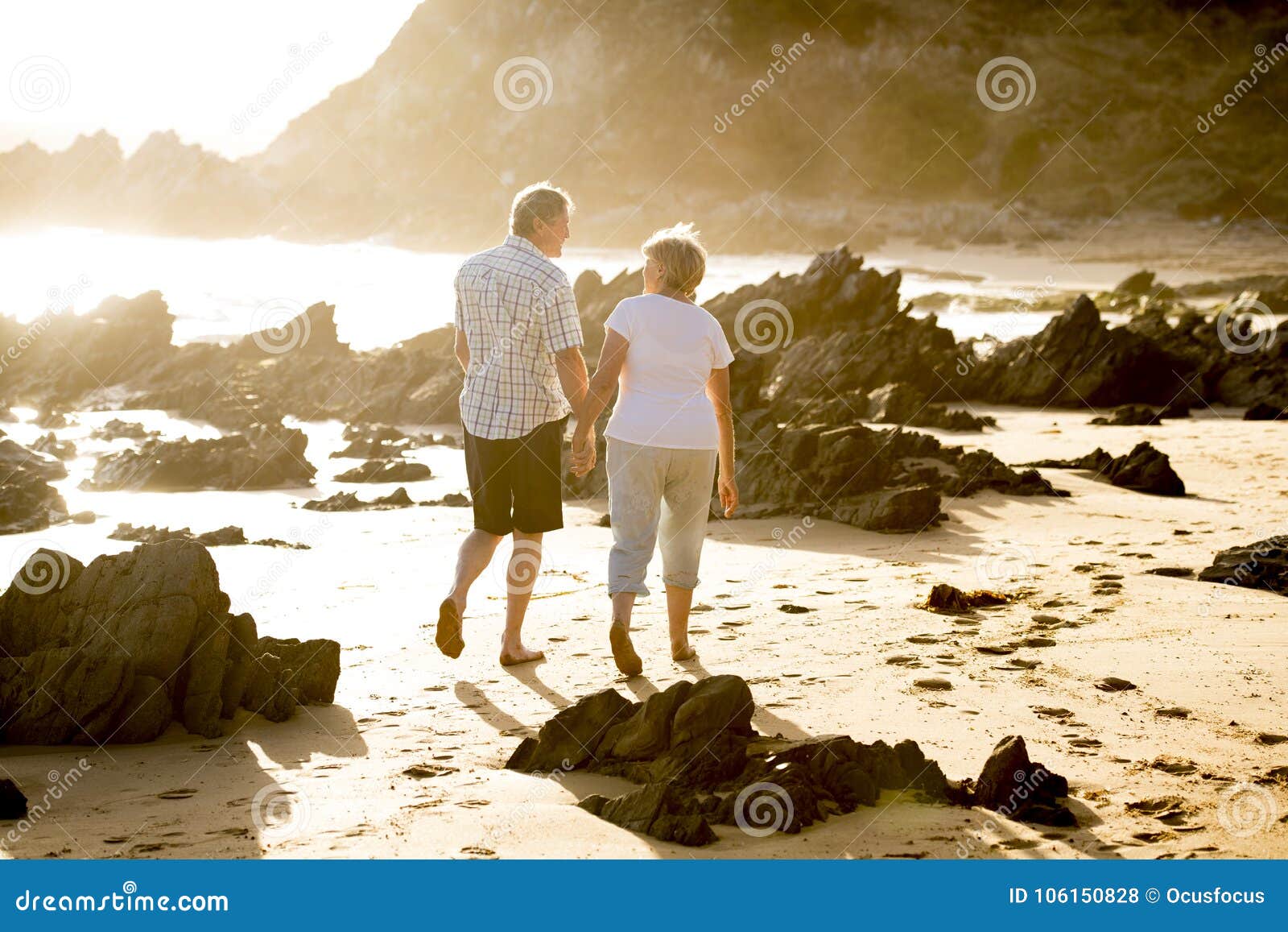 lovely senior mature couple on their 60s or 70s retired walking happy and relaxed on beach sea shore in romantic aging together