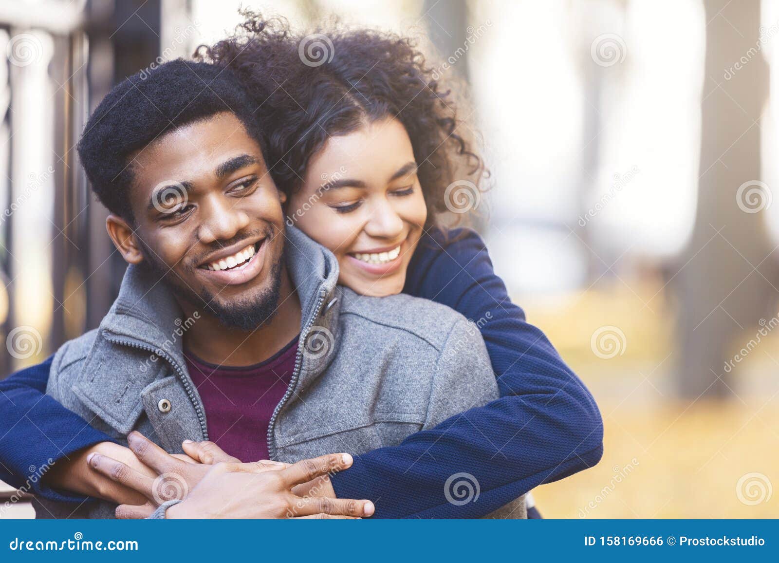 lovely black couple cuddling while date in autumn park