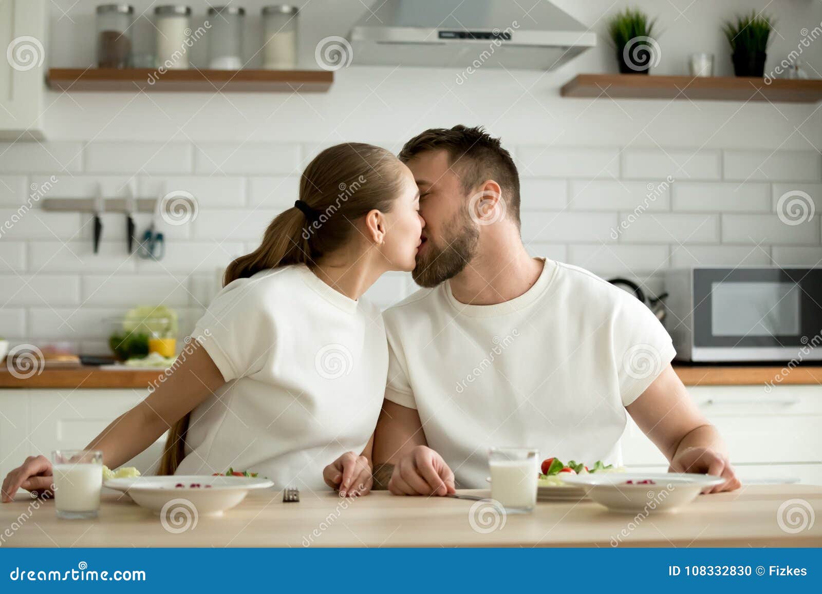 The Lovers Getting Hot In The Kitchen Loving Couple Enjoying Meal Kissing Sitting at Dining Kitchen Ta Stock