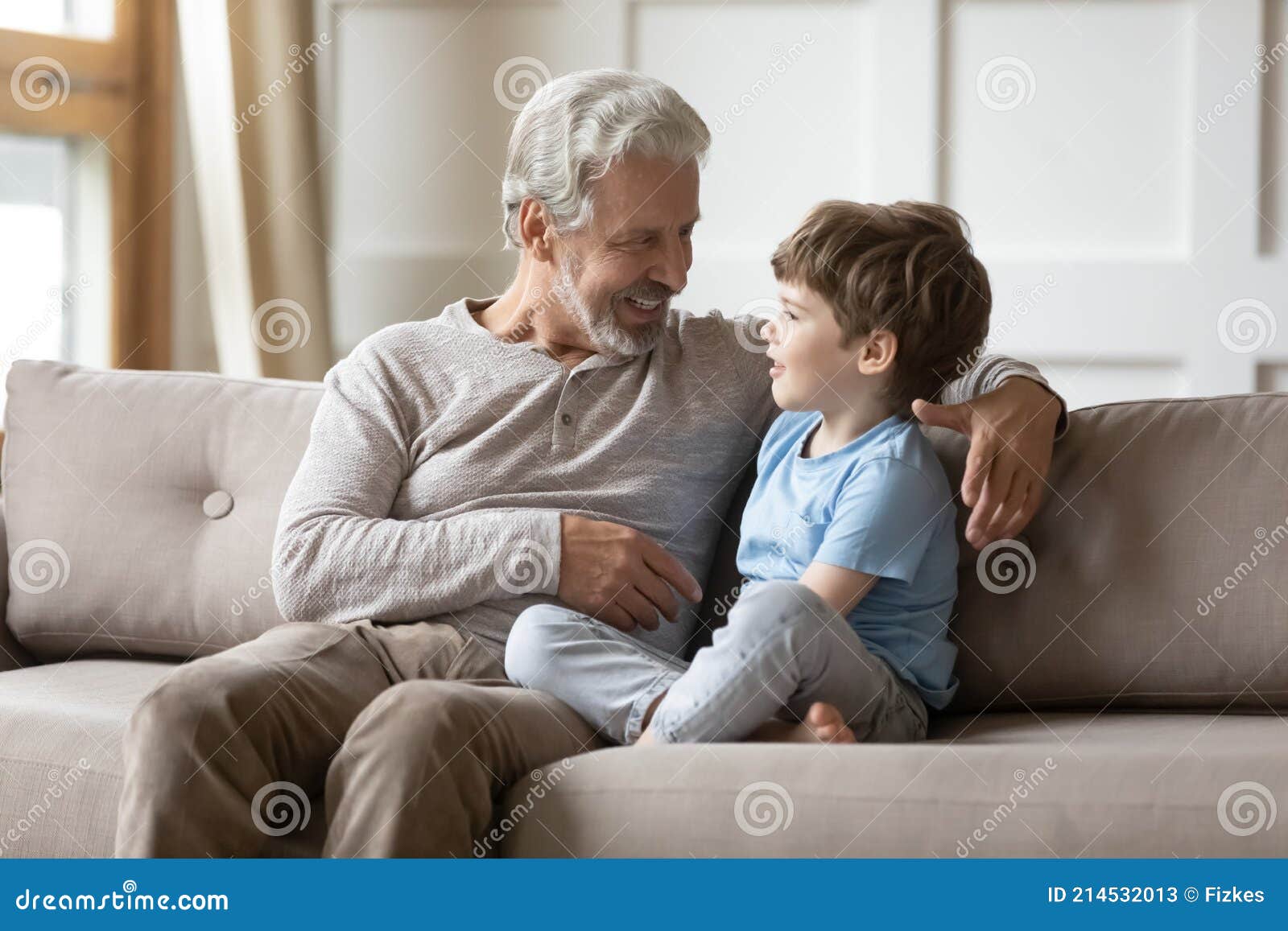 loving granddad sit on sofa talking with small grandson