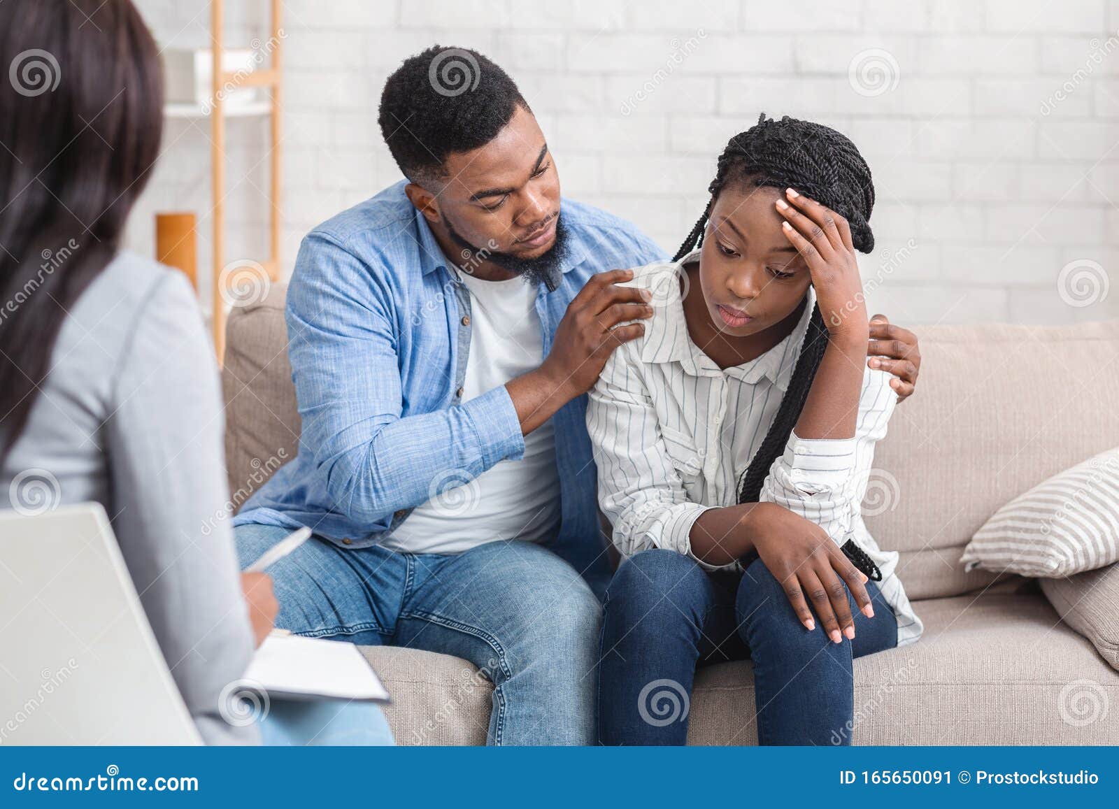 loving husband supporting his depressed wife during psychotherapy session with counselor