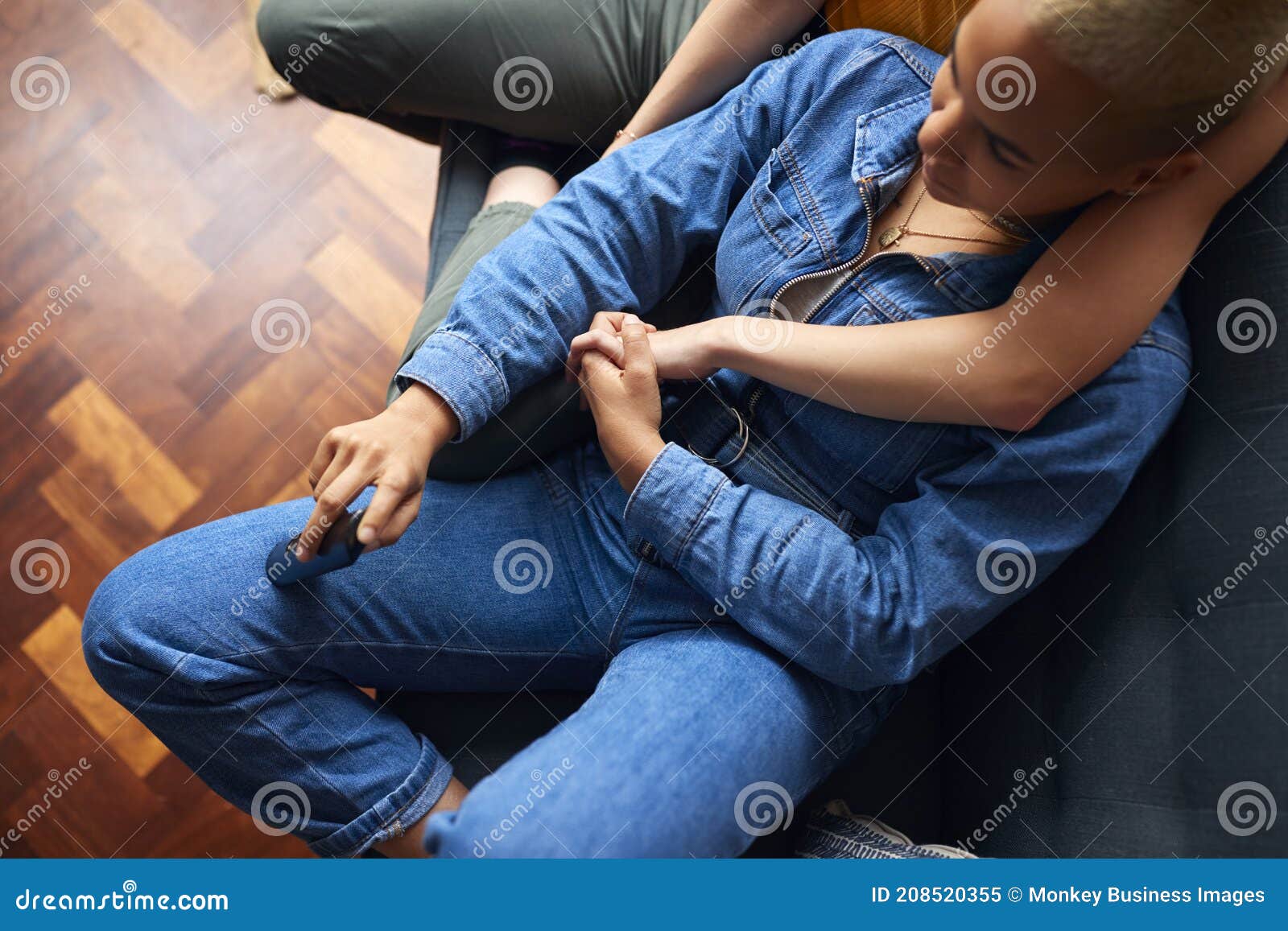 Loving Same Sex Female Couple Holding Hands Lying On Sofa