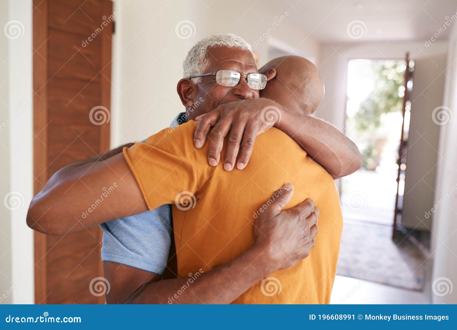 loving senior father hugging adult son indoors at home