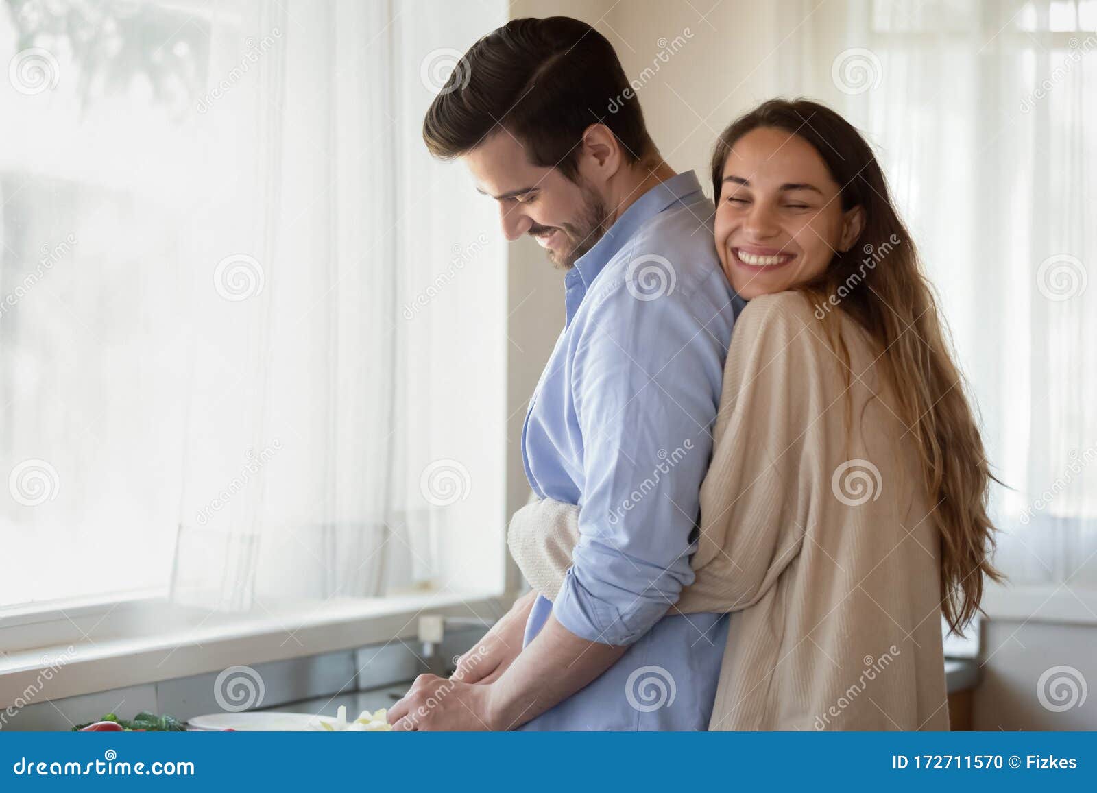 loving young newlyweds cuddle cooking at home together