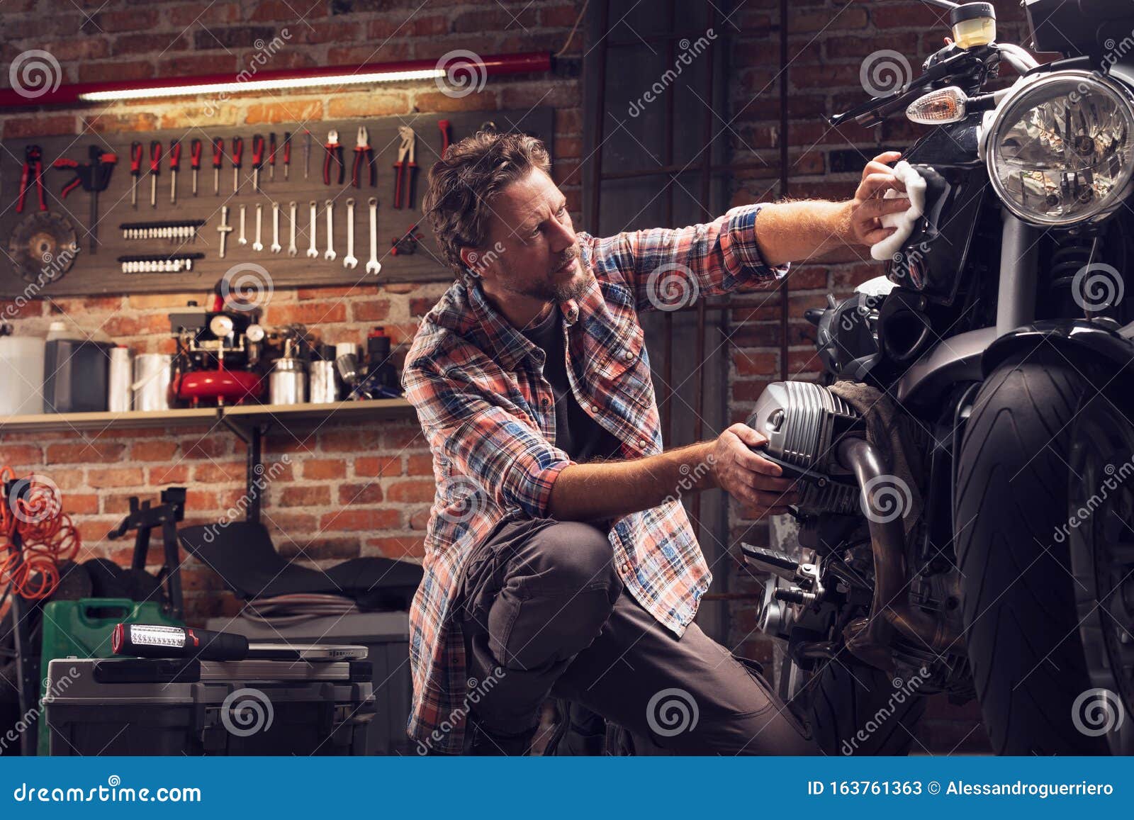 man polish motorcycle in garage