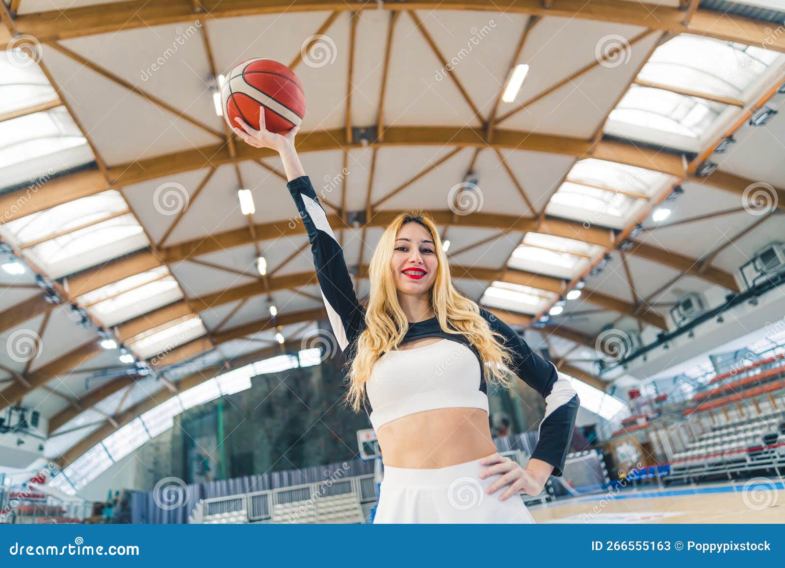 Low Angle Shot Of A Blond Cheerleader With A Stretched Arm Holding A