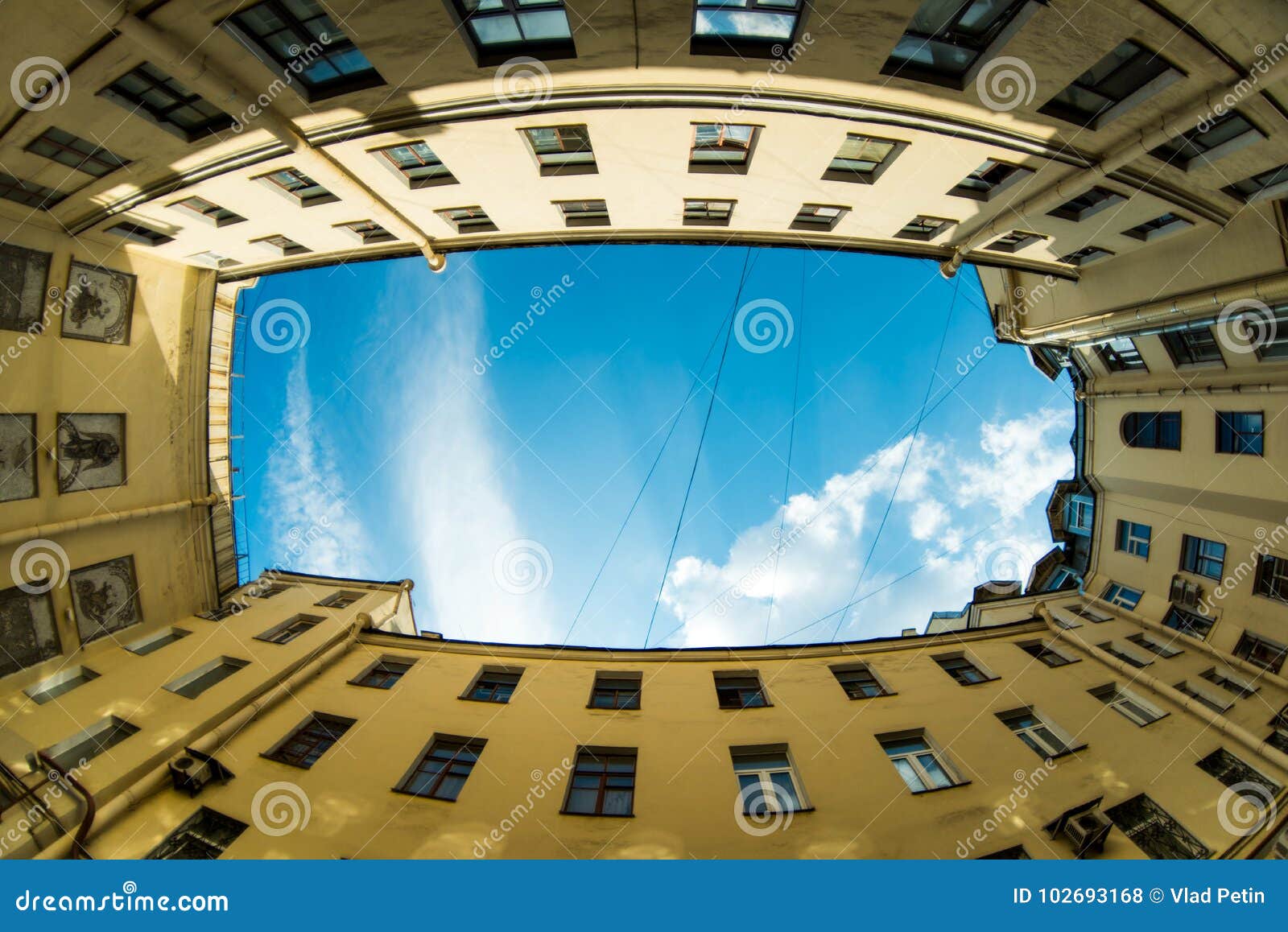 low angle shot of building with windows and cloudy sky background. courtyard city fisheye up view