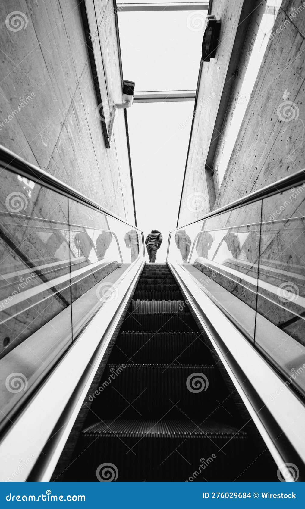 low angle shot of a man stepping off a grey metal escalator in a modern building