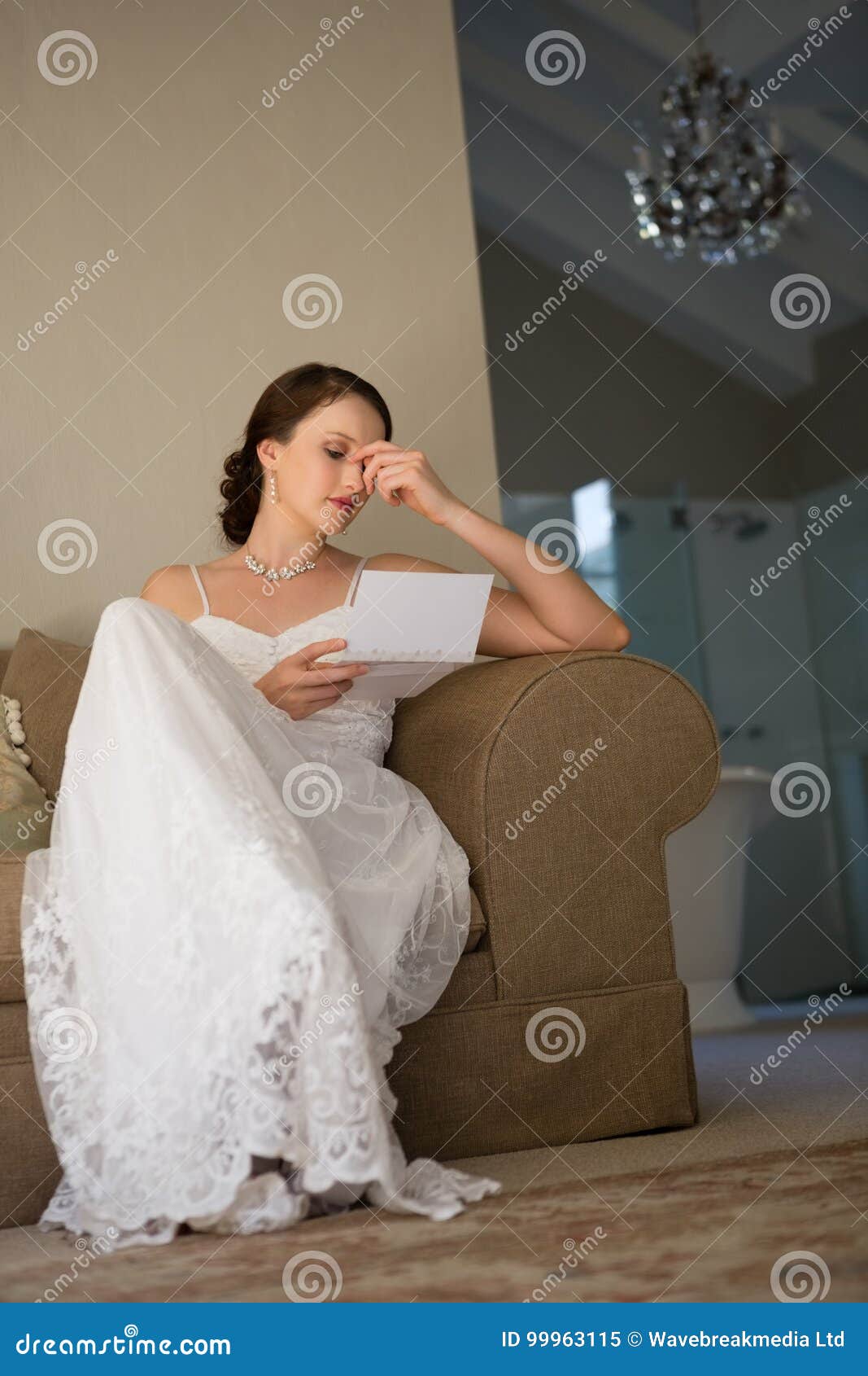 Low Angle View of Beautiful Bride Reading Wedding Card while Sitting on