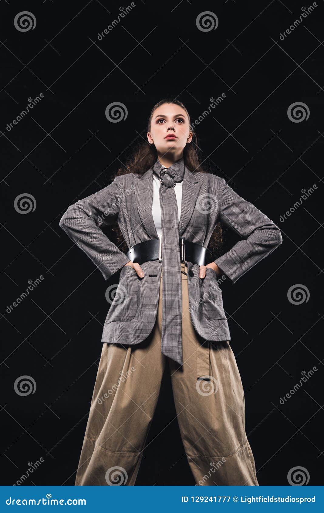 low angle view of confident young woman with hands on waist posing