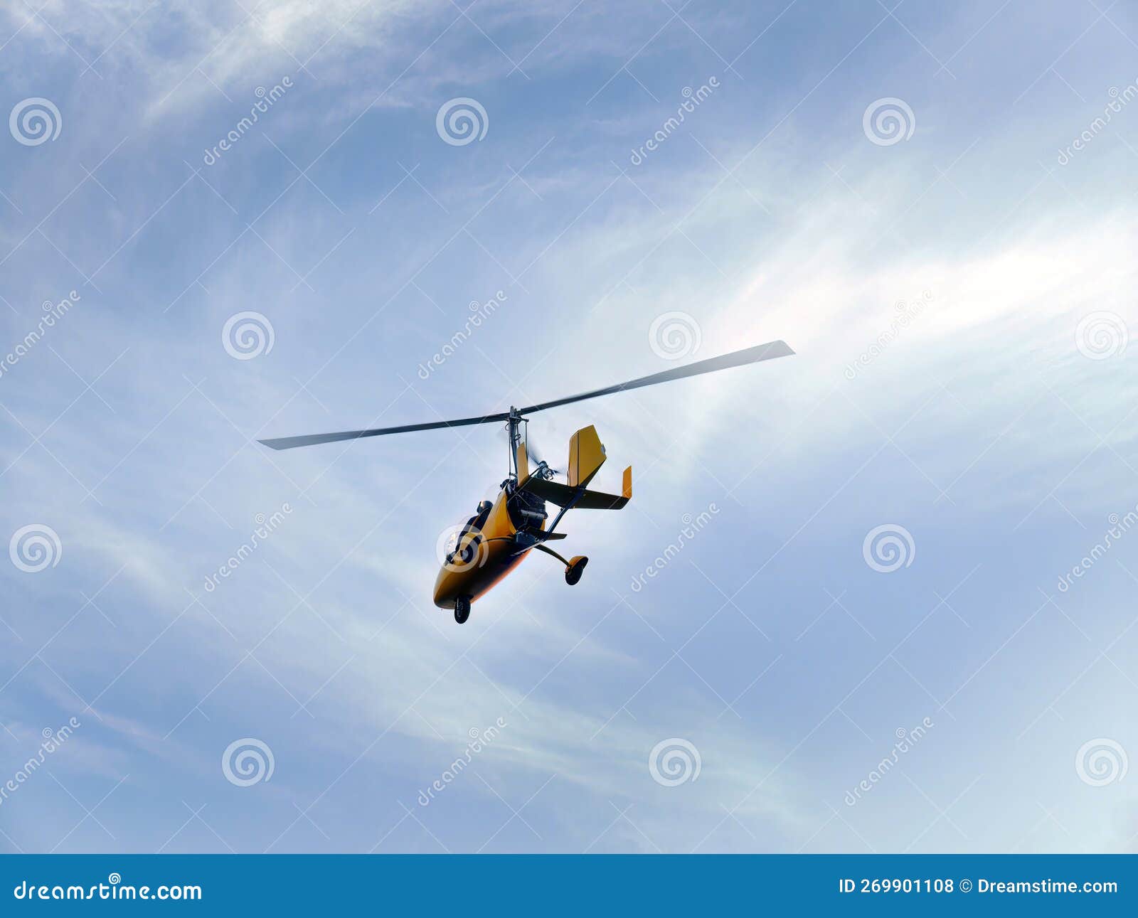 low angle view of yellow color gyrocopter flying in the blue sky and dramatic clouds, fun fly, aero sports, skydive, roto craft,