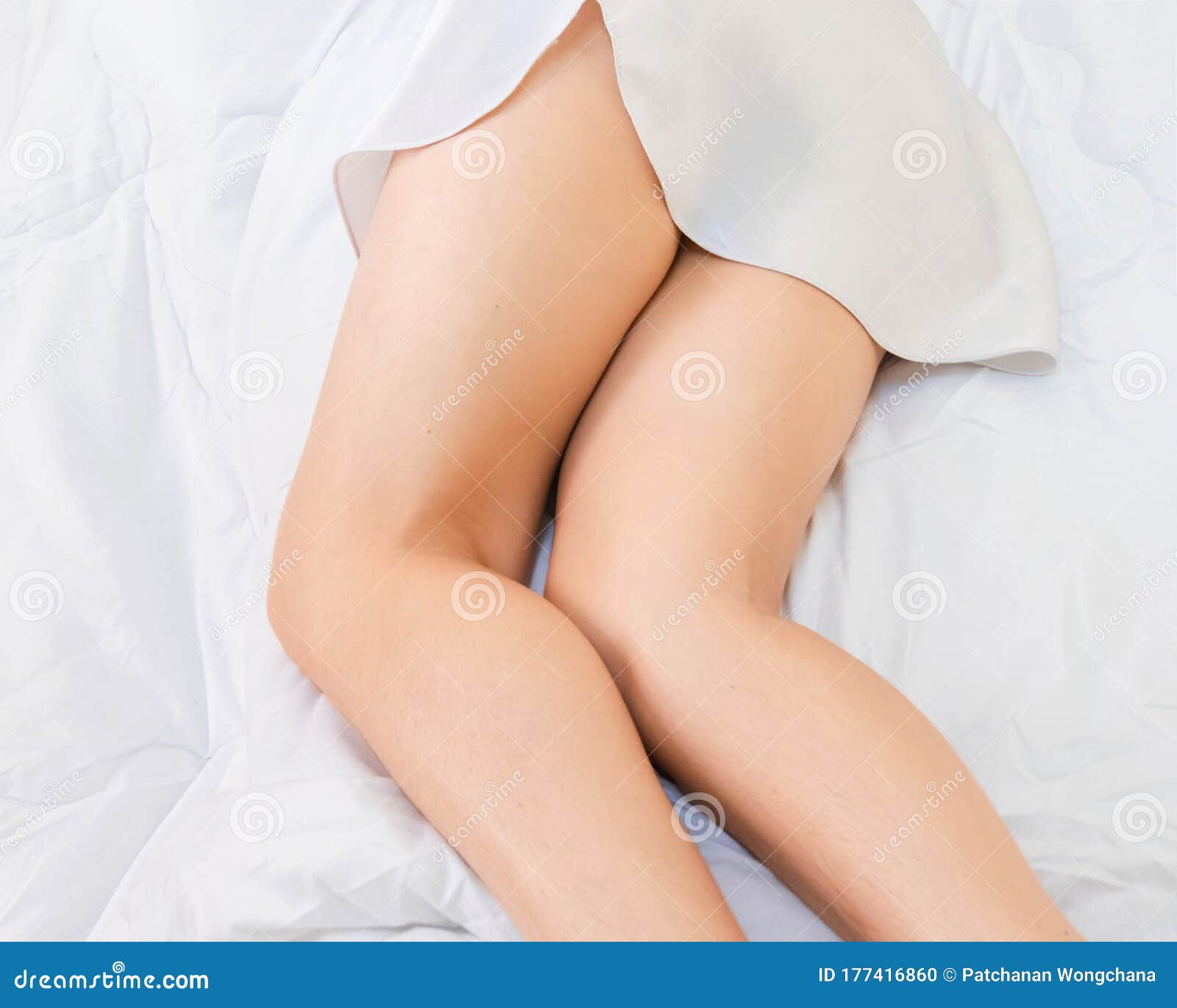 Lower Part of Female Body Wearing White Sleepwear Lying on Bed