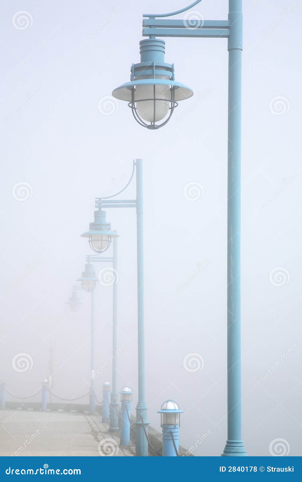 Luces de calle en niebla. Una serie de luces de calle decorativas que retroceden en la niebla.