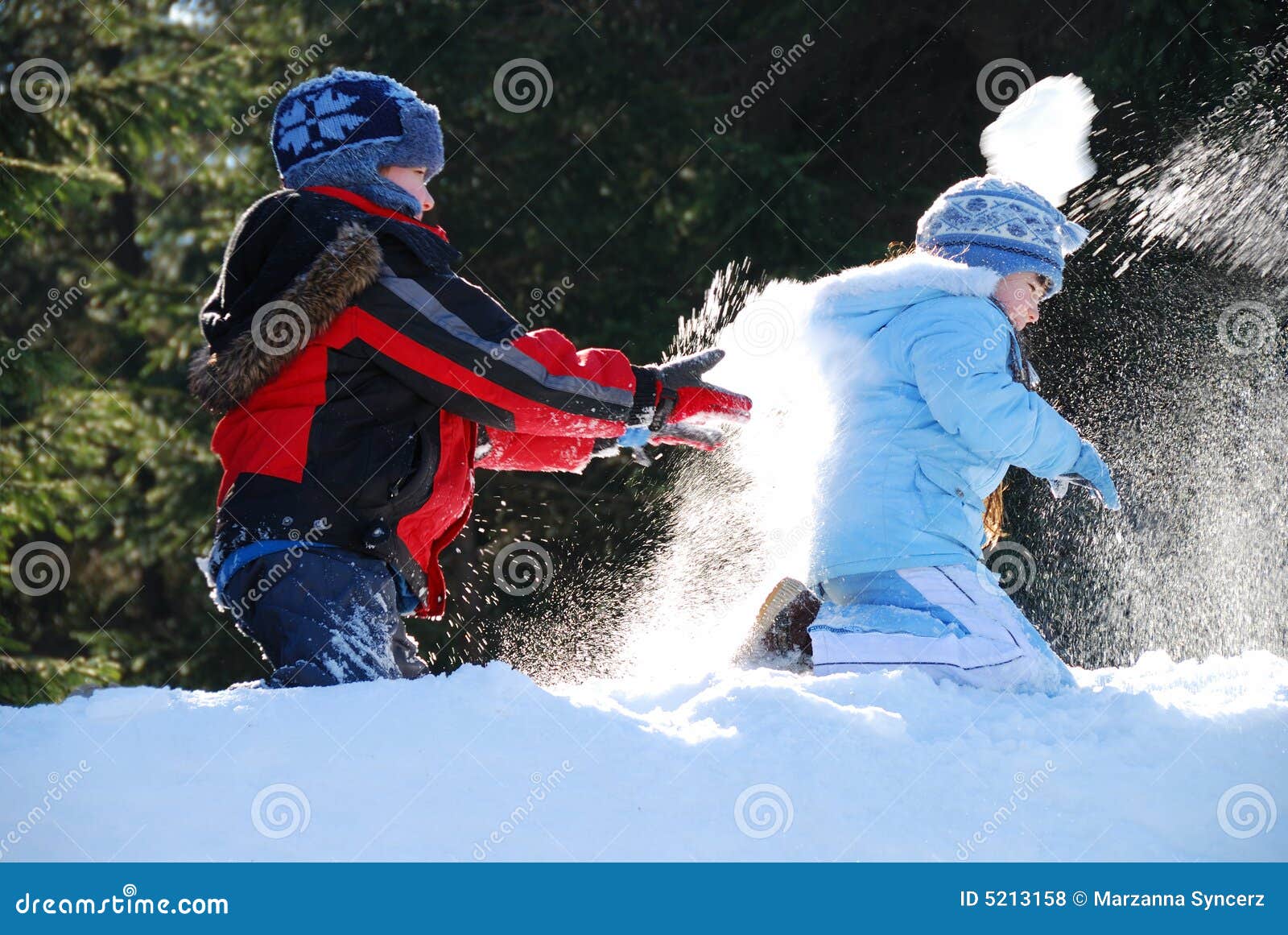 Niños lindos que desgastan la ropa caliente, teniendo una lucha de la bola de nieve