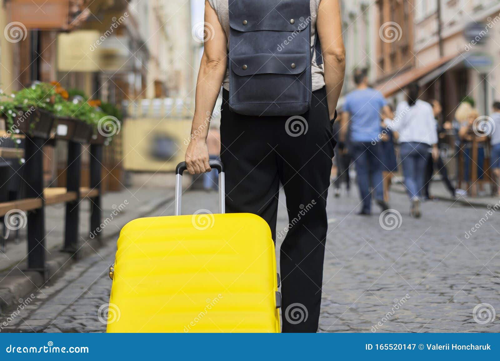 luggage travel tourism concept, closeup of yellow suitcase in hand of walking woman