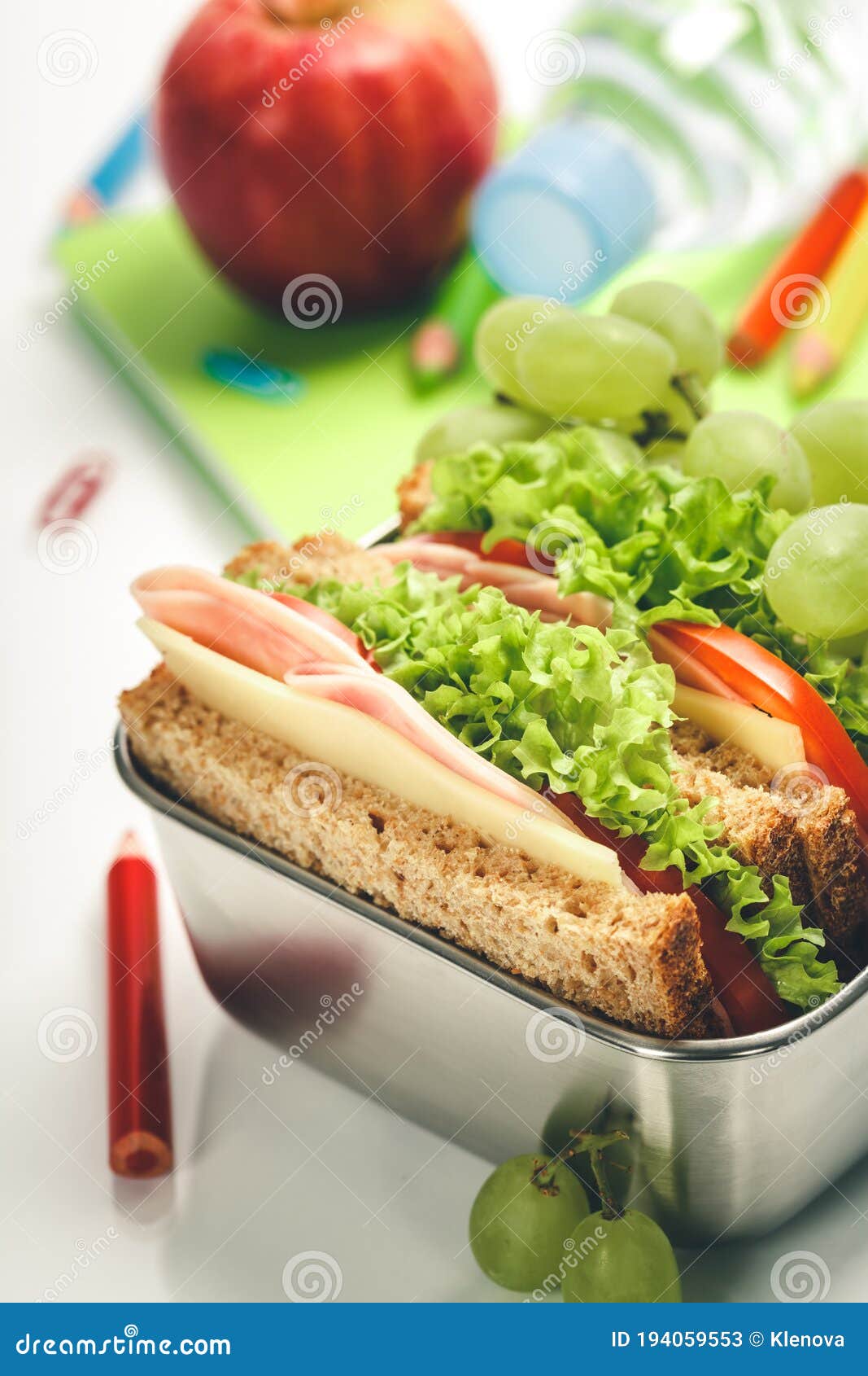 Lunch box with sandwich and apple on white background